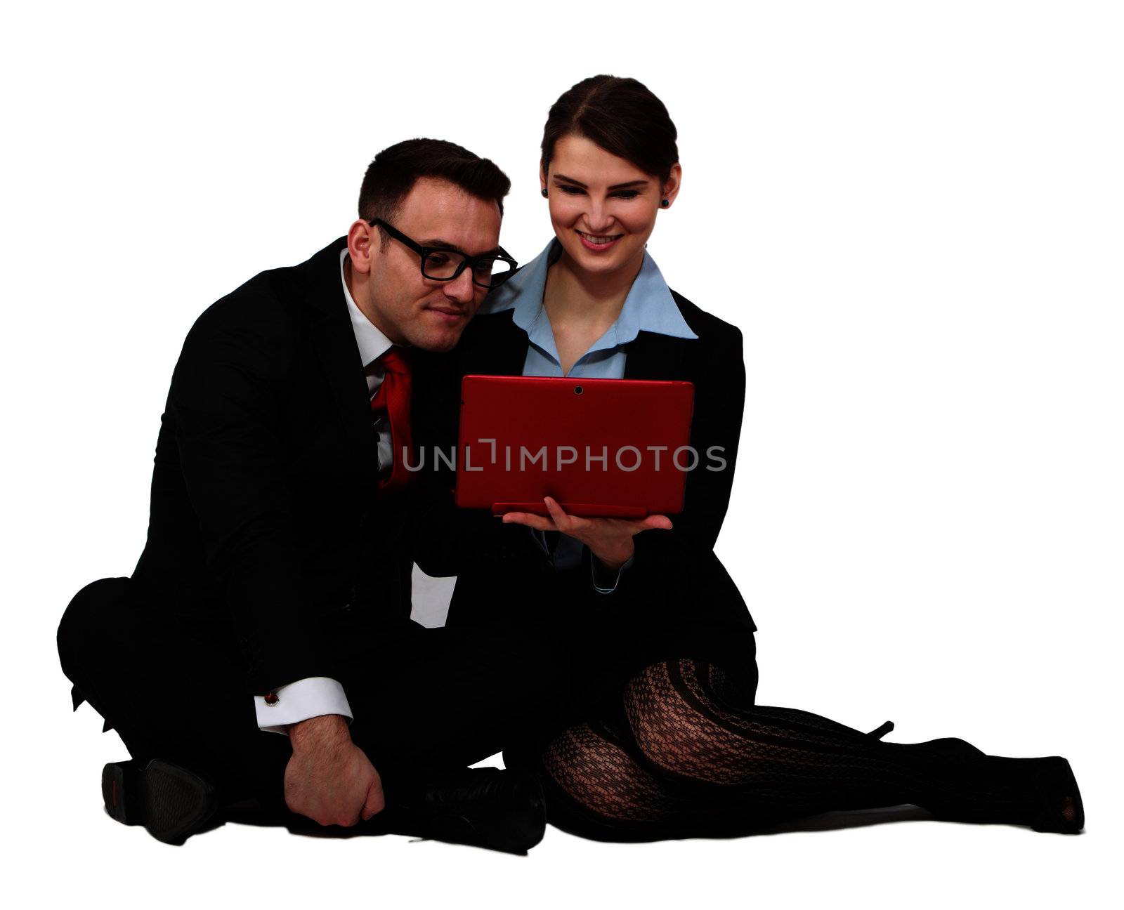 Young business couple looking together to the notebook while sitting against a white background.