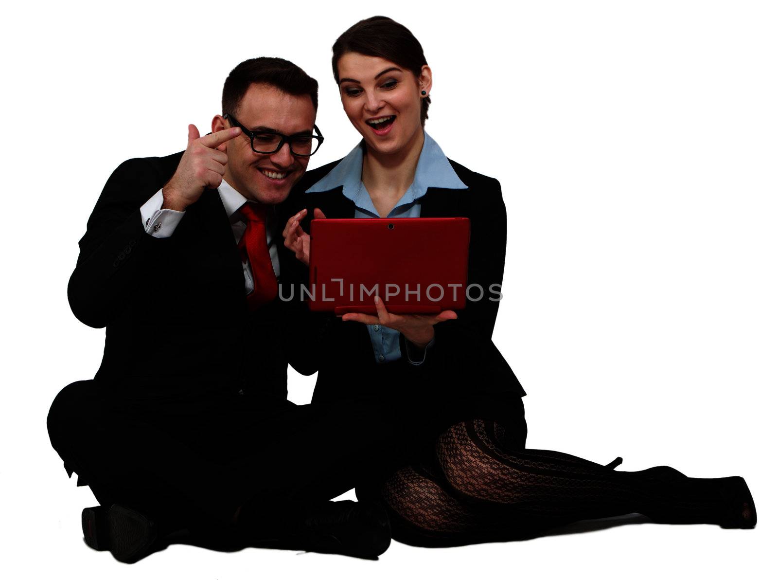 Happy young business couple looking at the notebook while sitting against a white background.