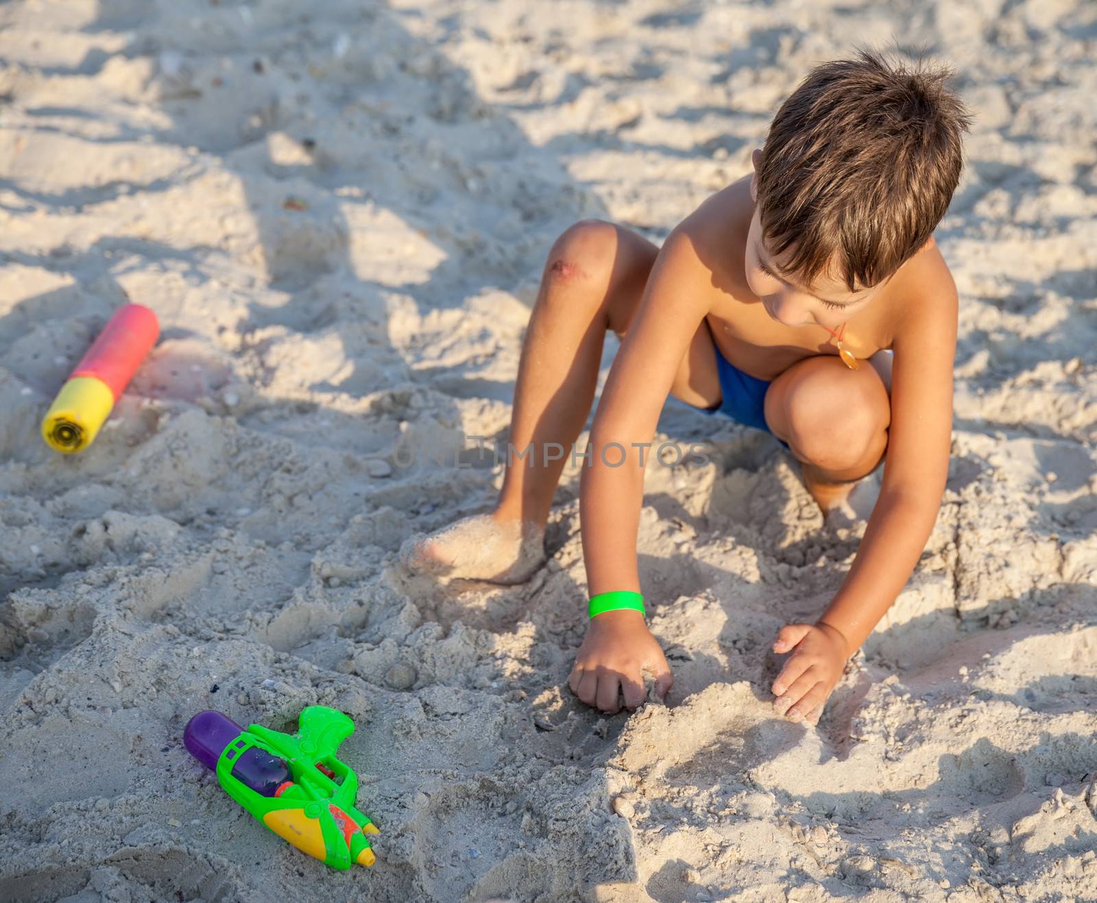 boy playing with sand in the beach by palinchak