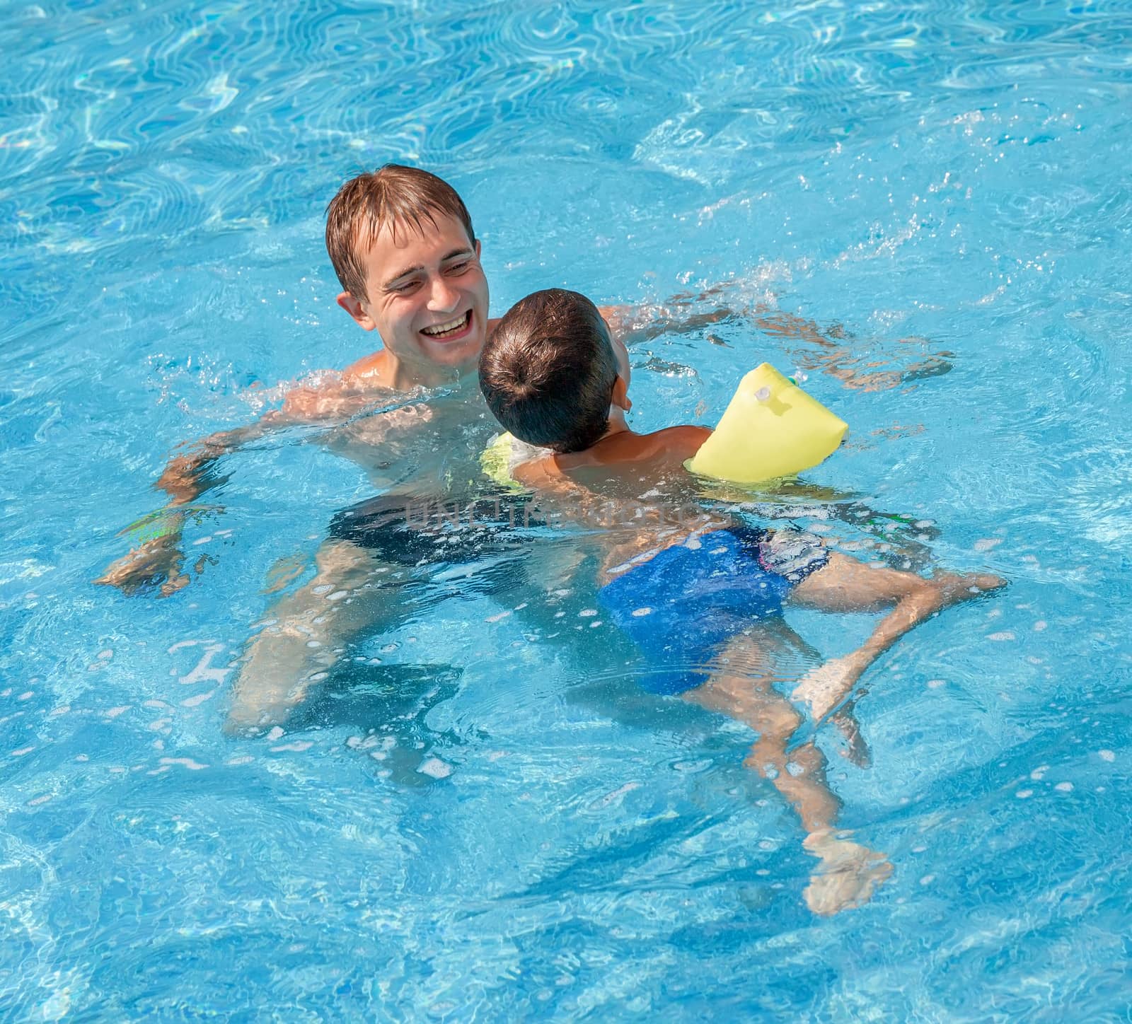 Father teaching his son to swim in the pool