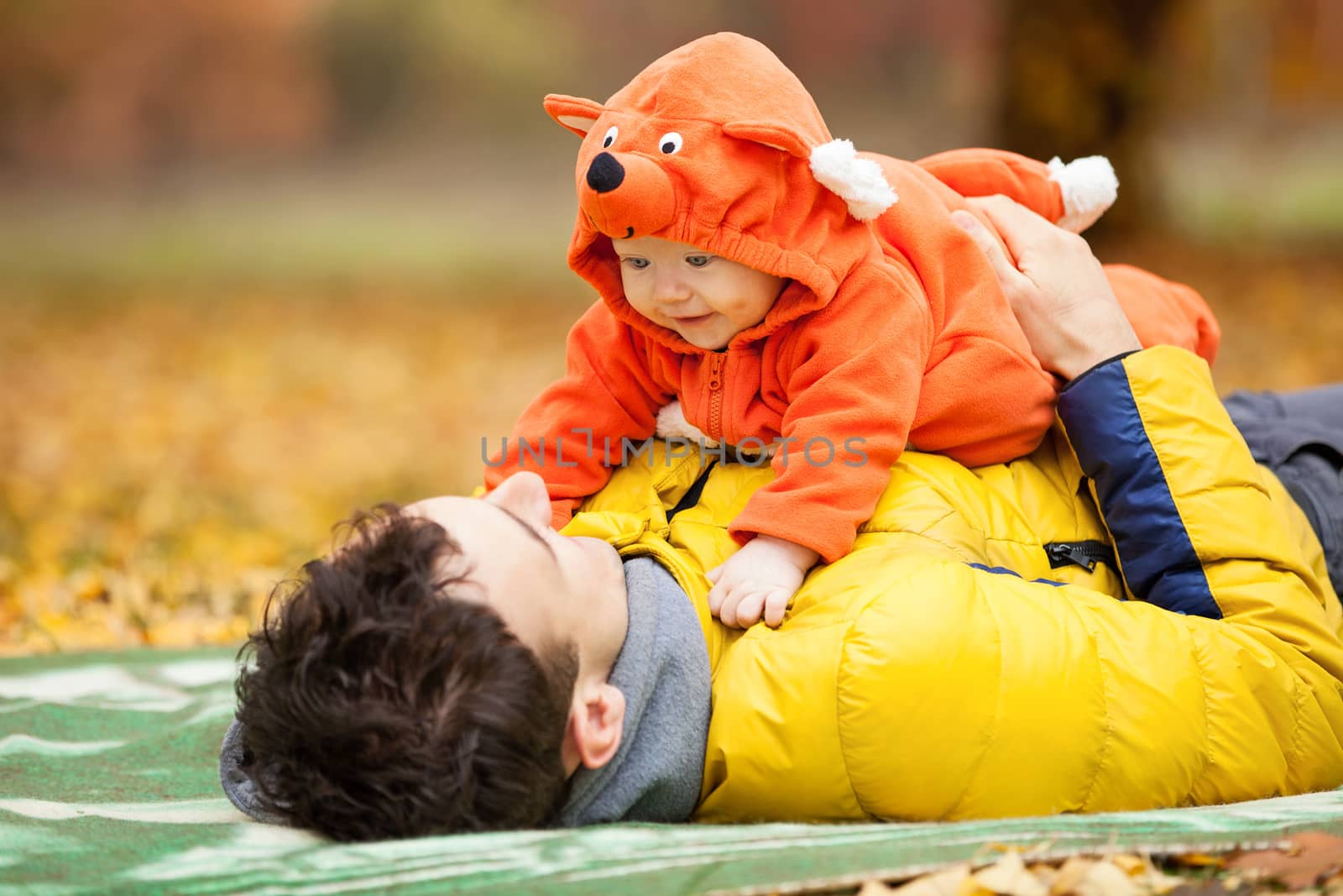Young father and his little son in fox costume having fun in autumn park