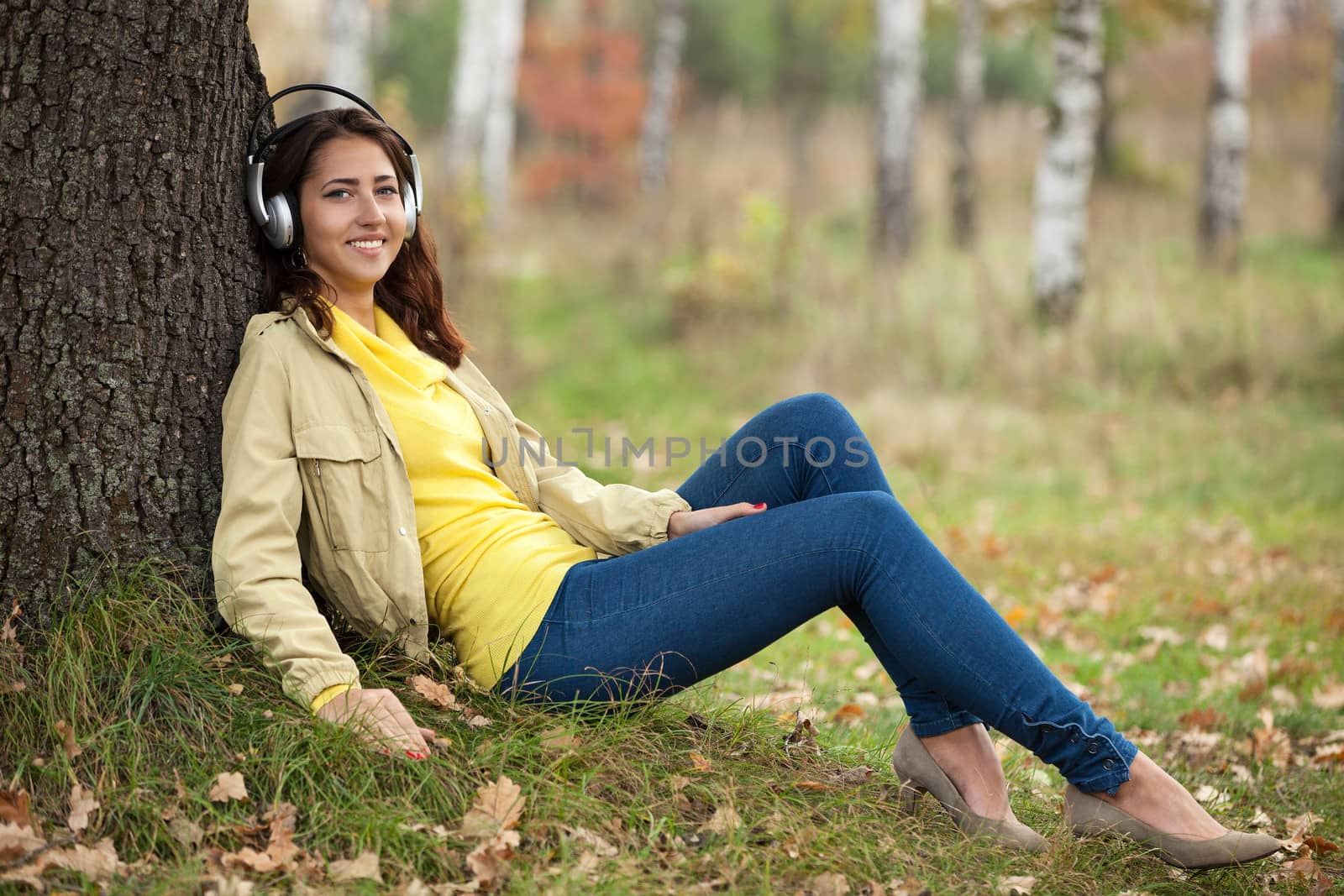 Young girl listening to music on headphones while sitting on grass