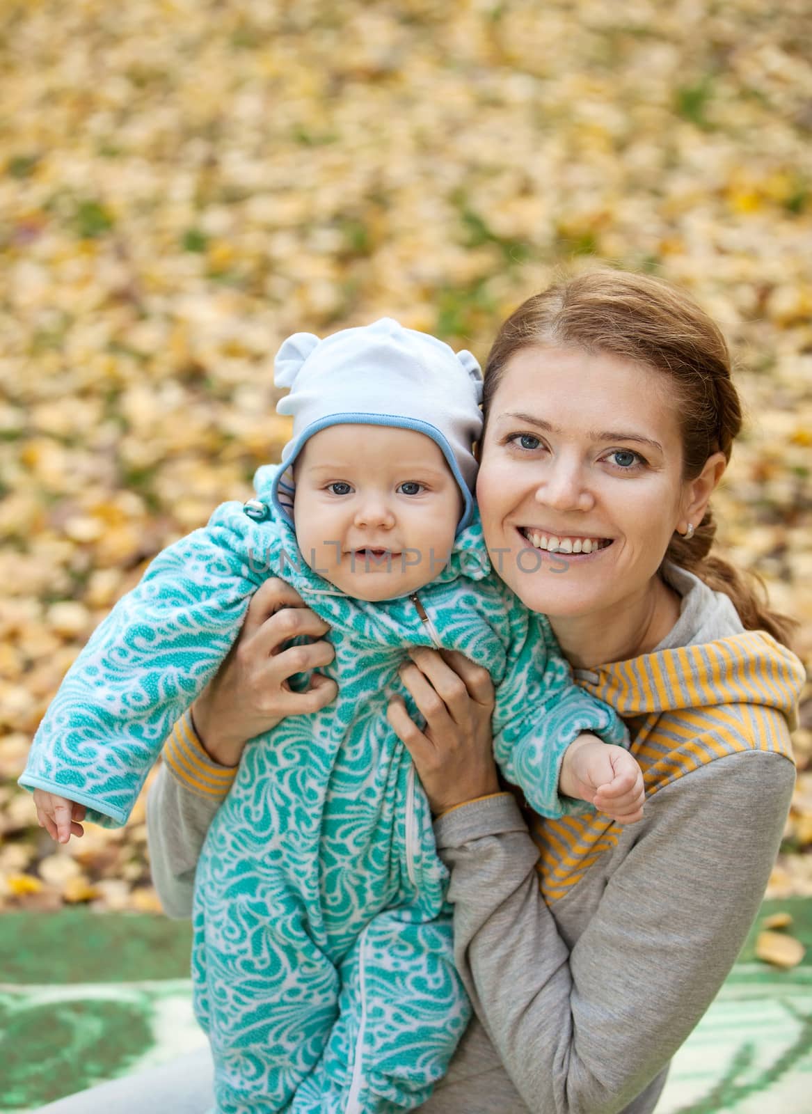 Portrait of young woman and her baby son in autumn park