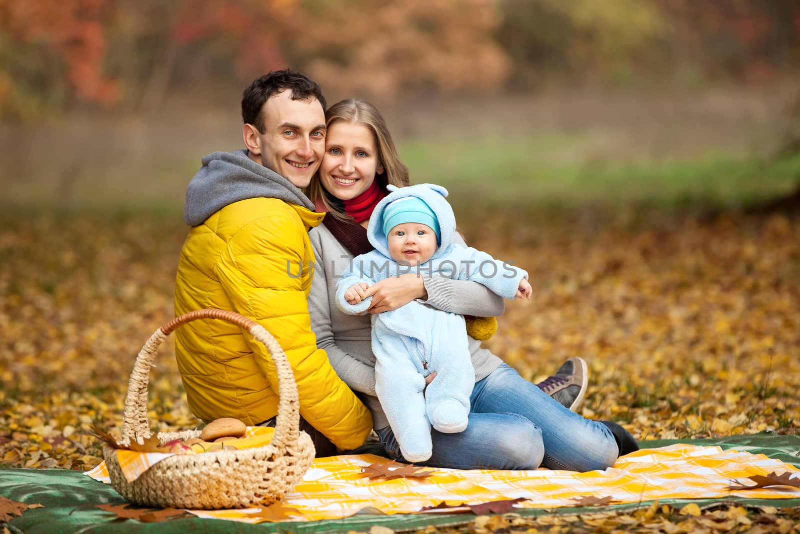 Young couple with baby boy on picnic in autumn park