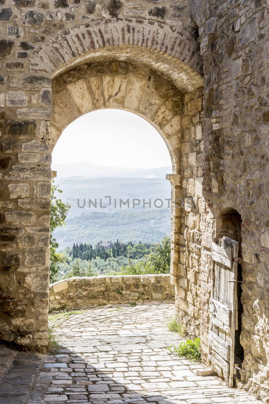 Archway in San Quirico with view to the Tuscan landscape in Tuscany, Italy