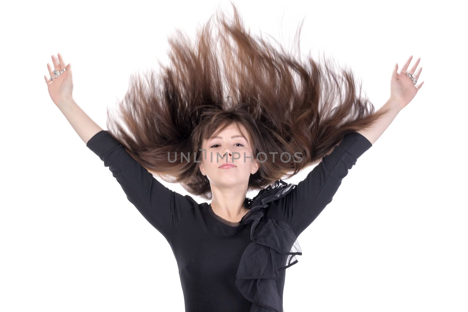 Young woman with her long straight brunette hair flying in the air and her arms raised above her head isolated on white