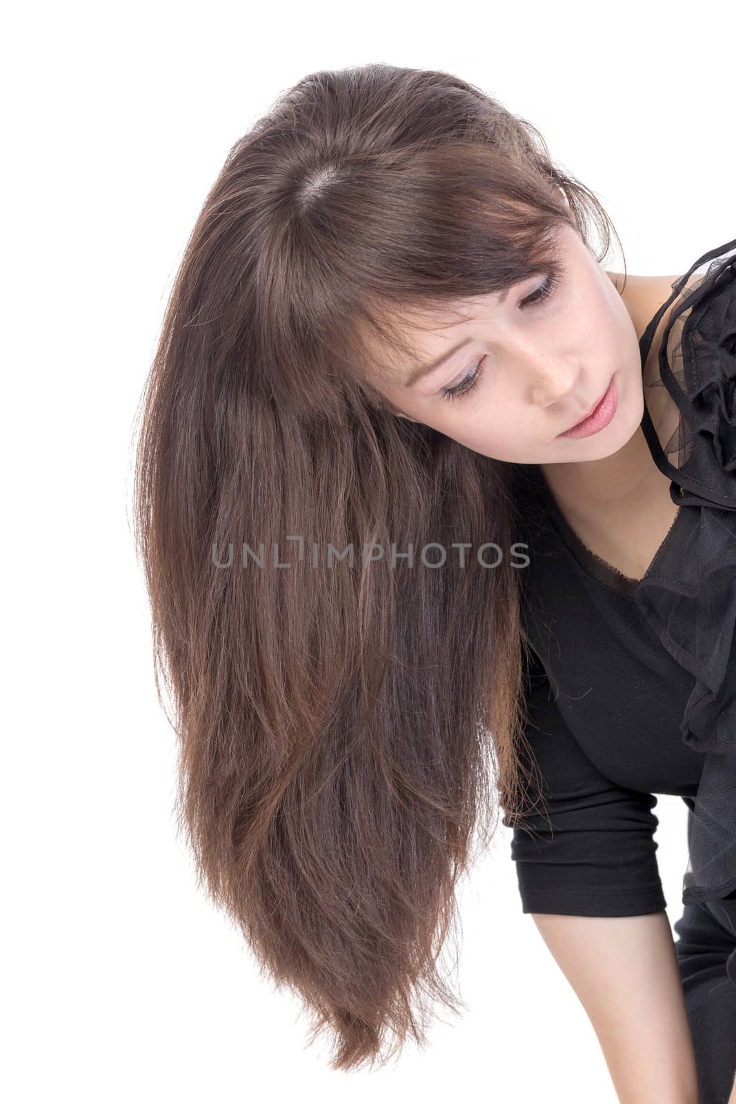 Attractive young woman with long brunette hair leaning sideways into the frame so that her hair falls straight down alongside her shoulder, isolated on white