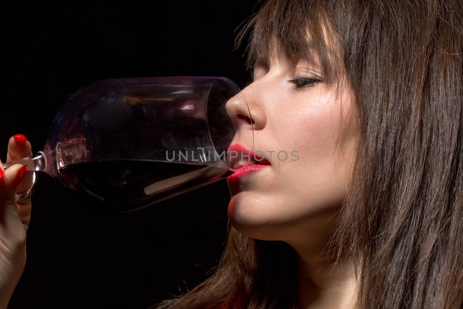 Young woman drinking red wine from a glass by Discovod