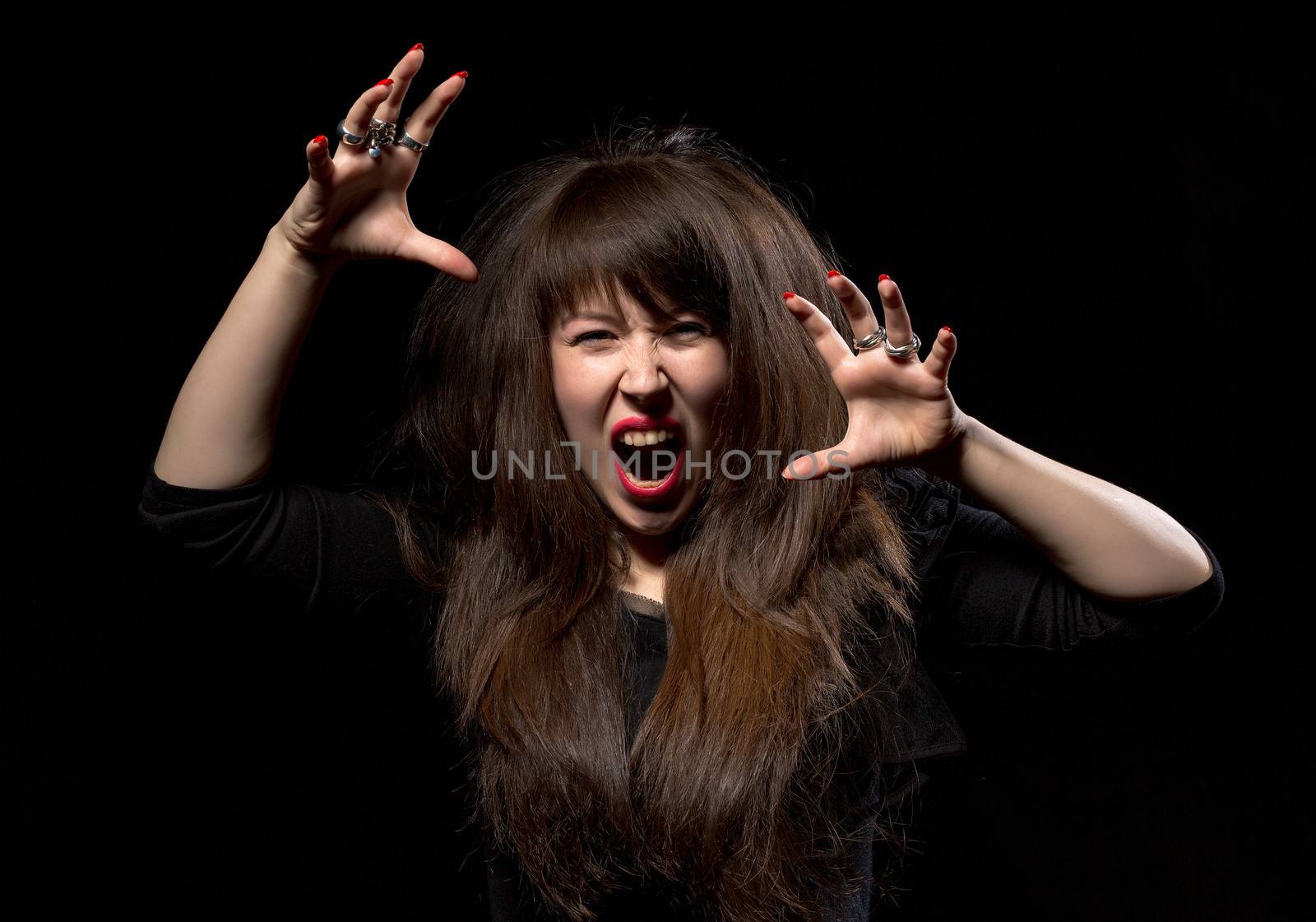 Woman throwing a temper tantrum screaming in anger and clawing the air with her hands on a dark background