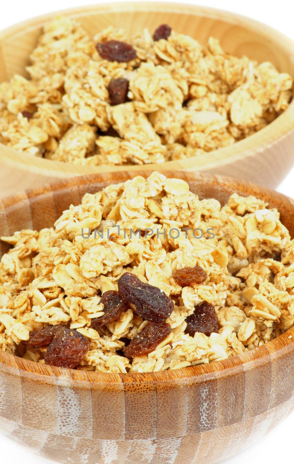 Breakfast Cereal Flakes with Slices of Nuts and Raisins closeup in Two Wooden Bowls