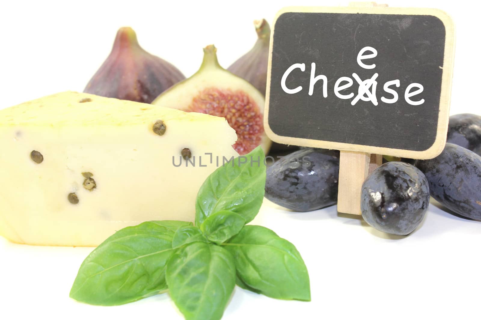 Piece of cheese with pepper, figs, grapes, basil and blackboard