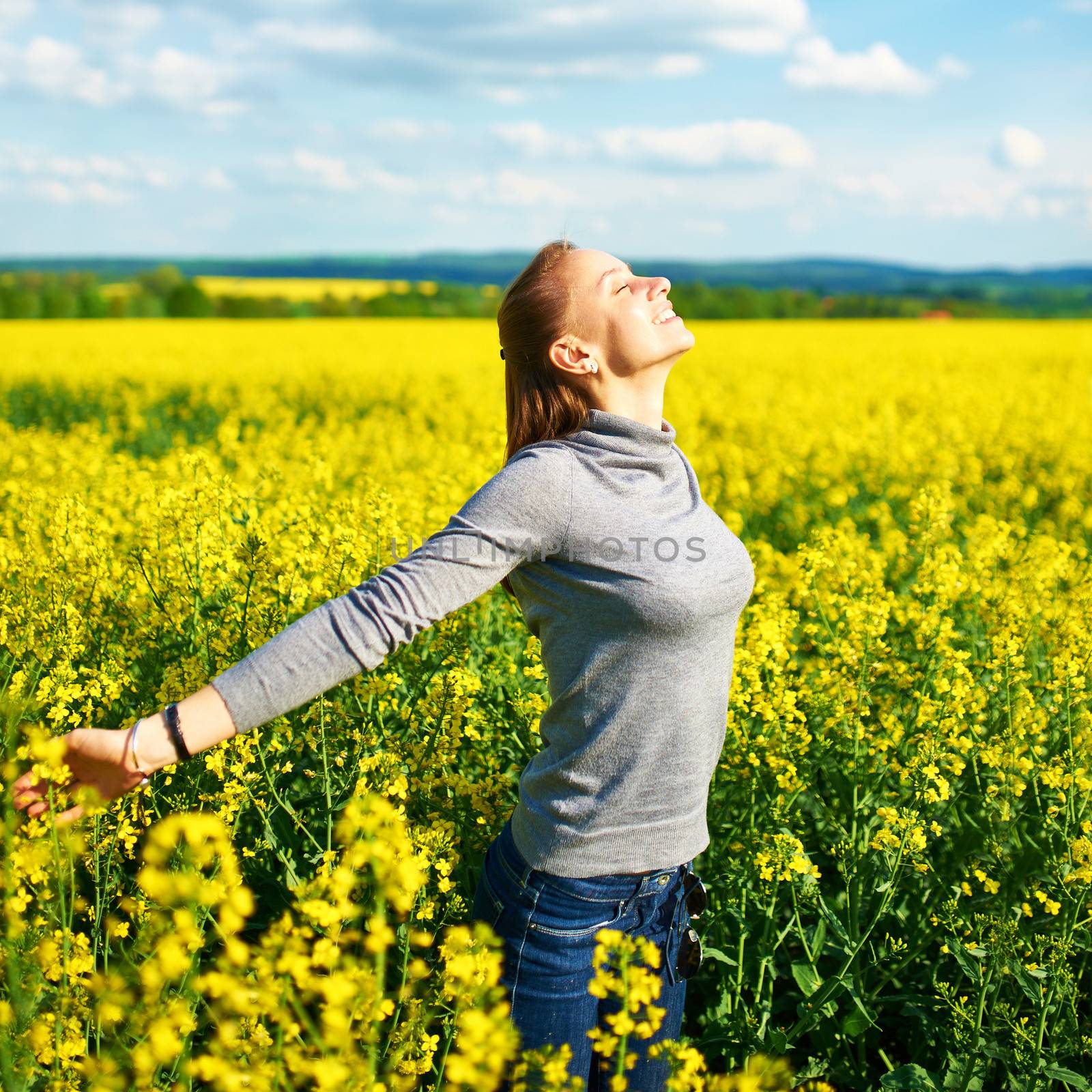 Girl with outstretched arms at colza field