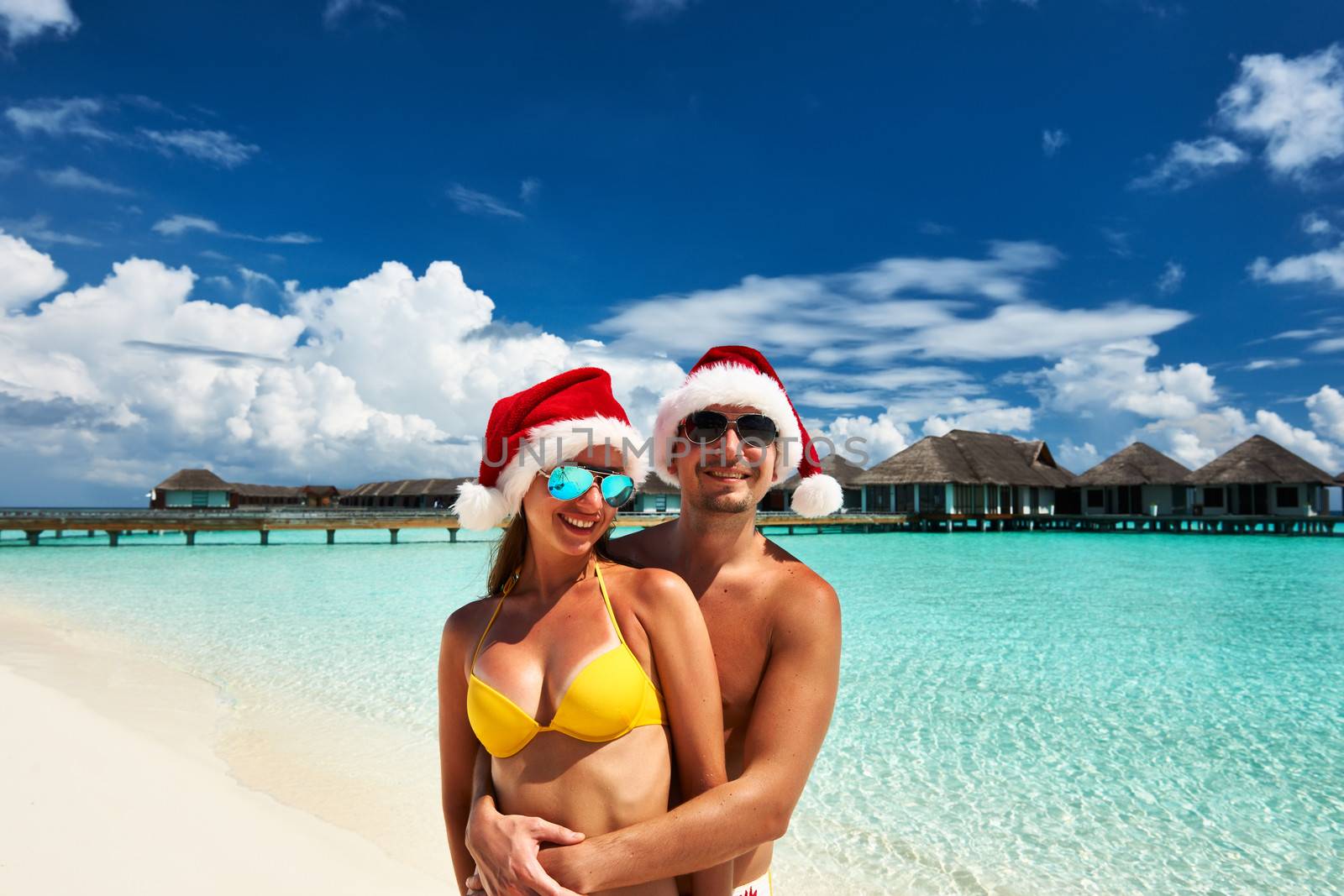 Couple in santa's hat on a tropical beach at Maldives