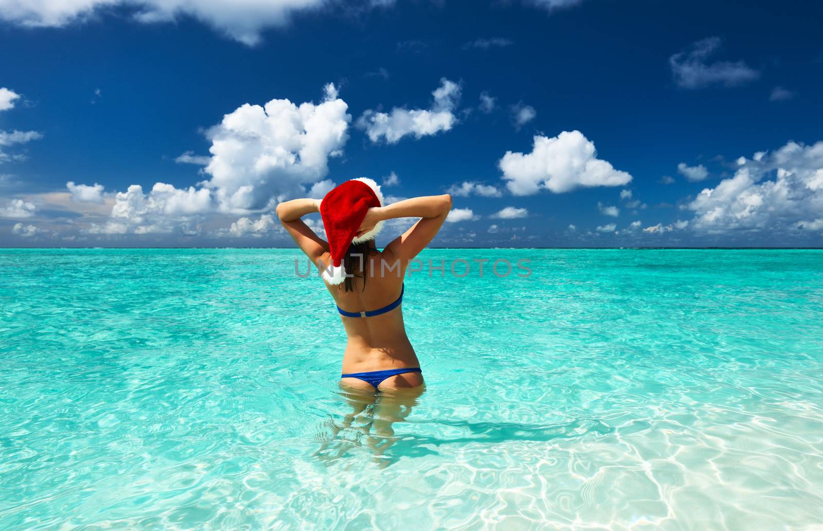 Woman in santa's hat at beach by haveseen