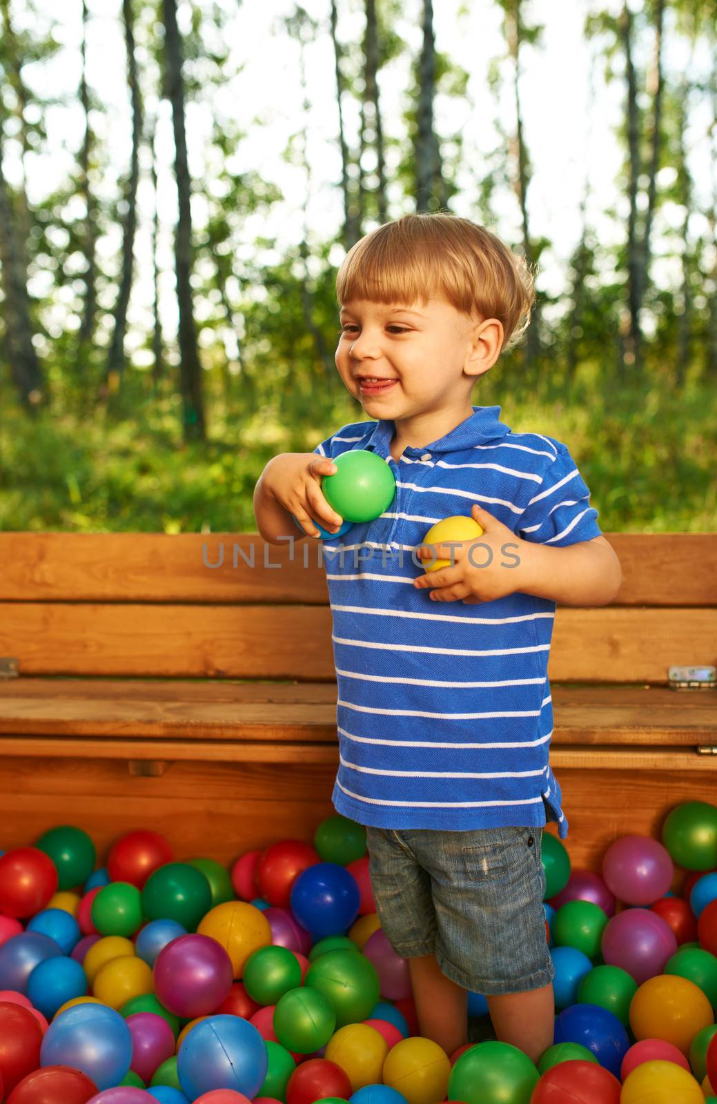 Happy child playing with colorful plastic balls by haveseen