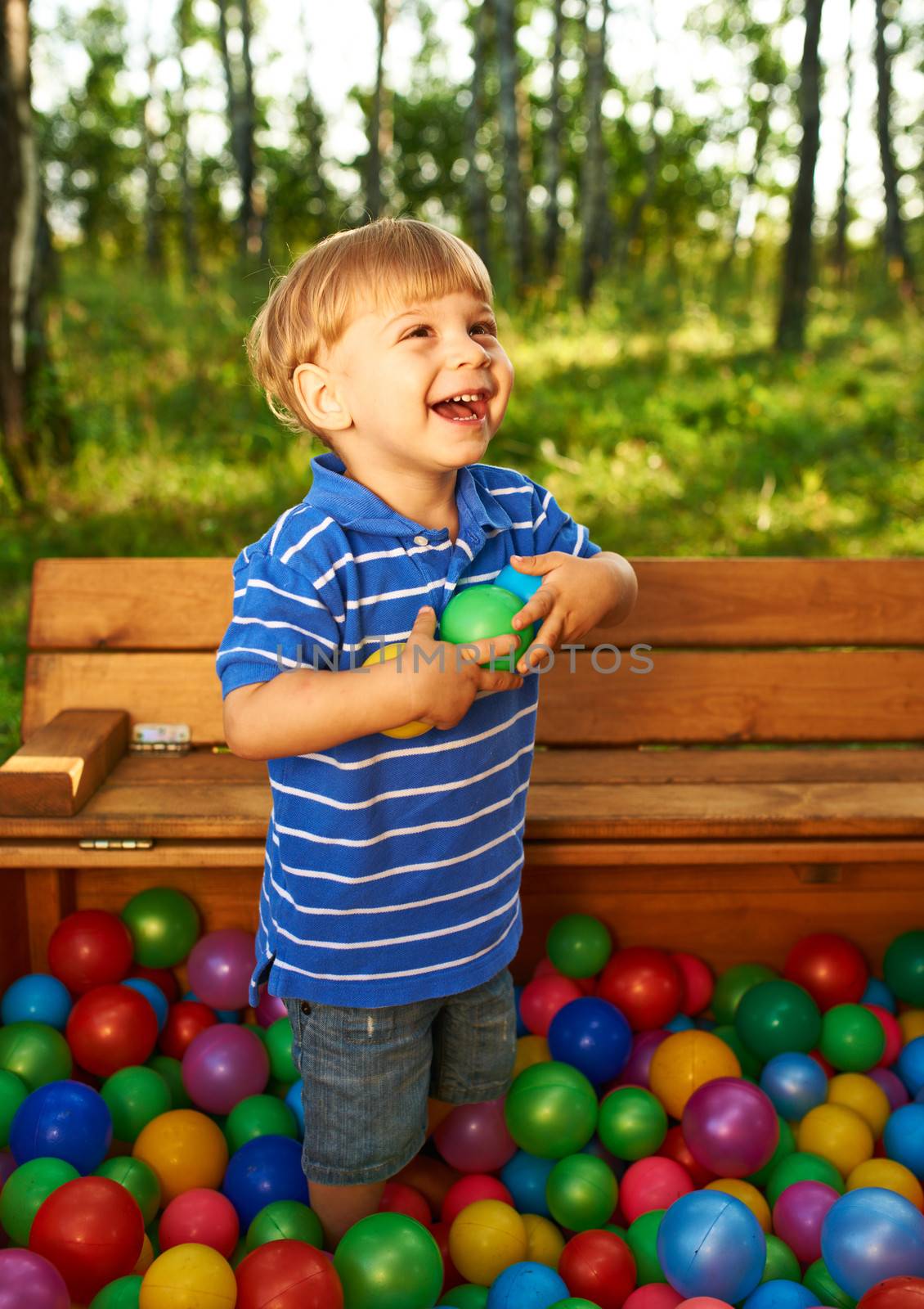 Happy child playing with colorful plastic balls by haveseen