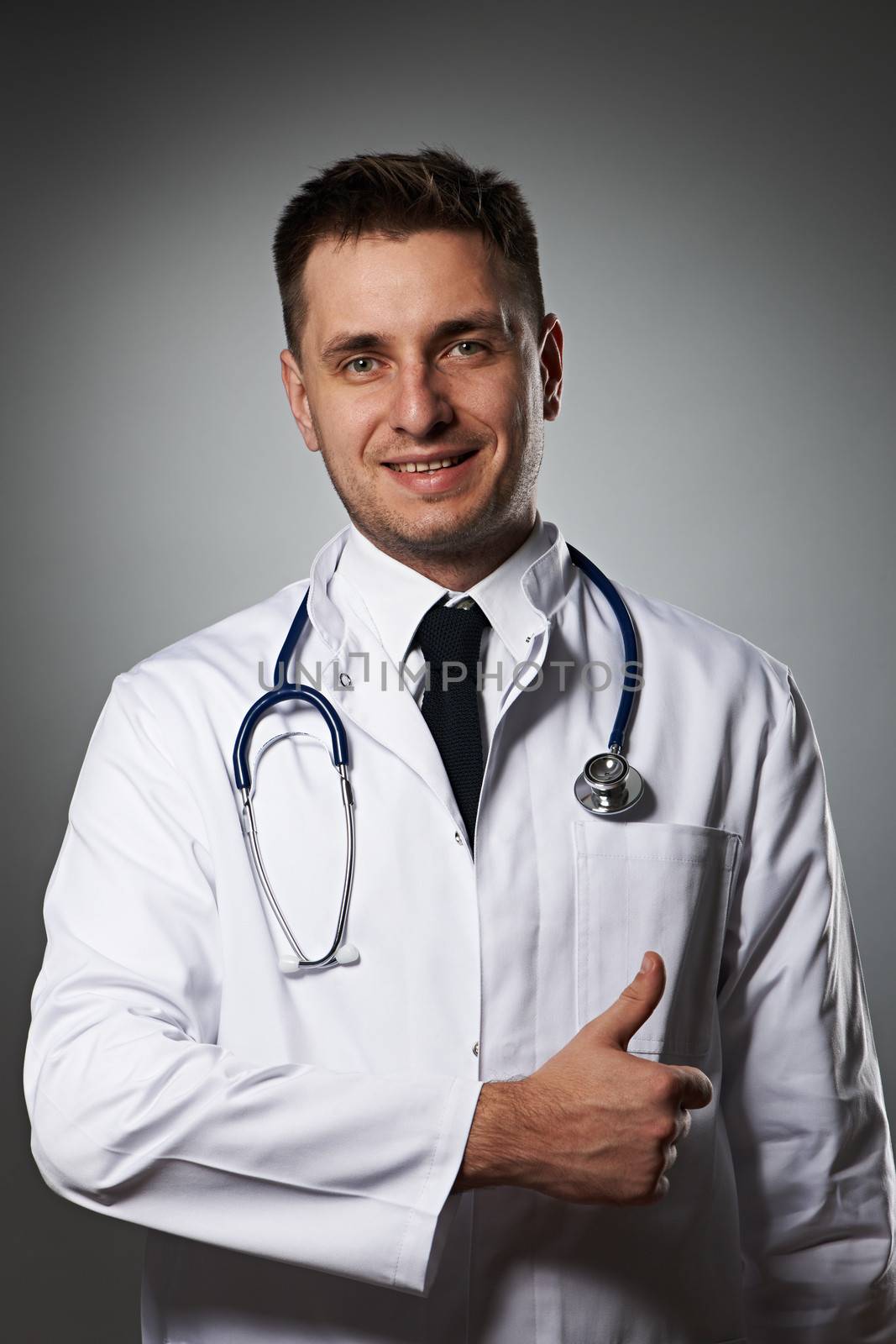 Medical doctor with thumb up portrait against grey background 