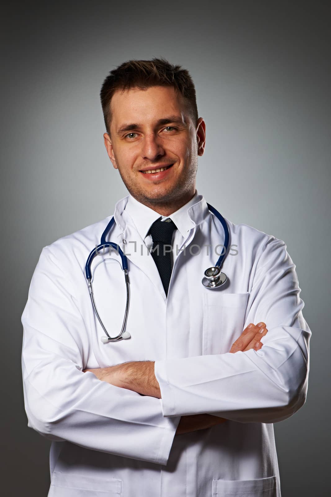 Medical doctor with stethoscope portrait against grey background 