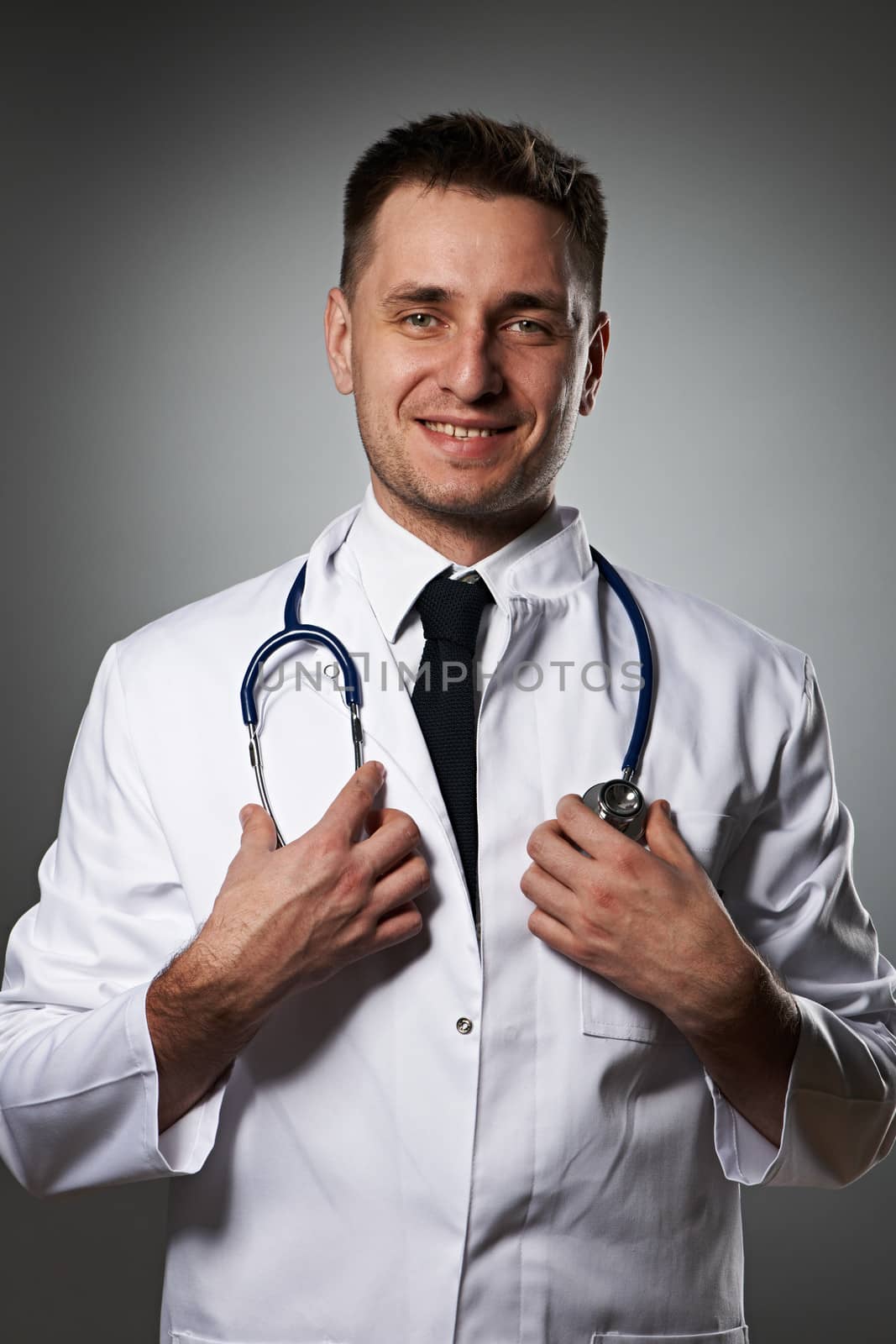 Medical doctor with stethoscope portrait against grey background 