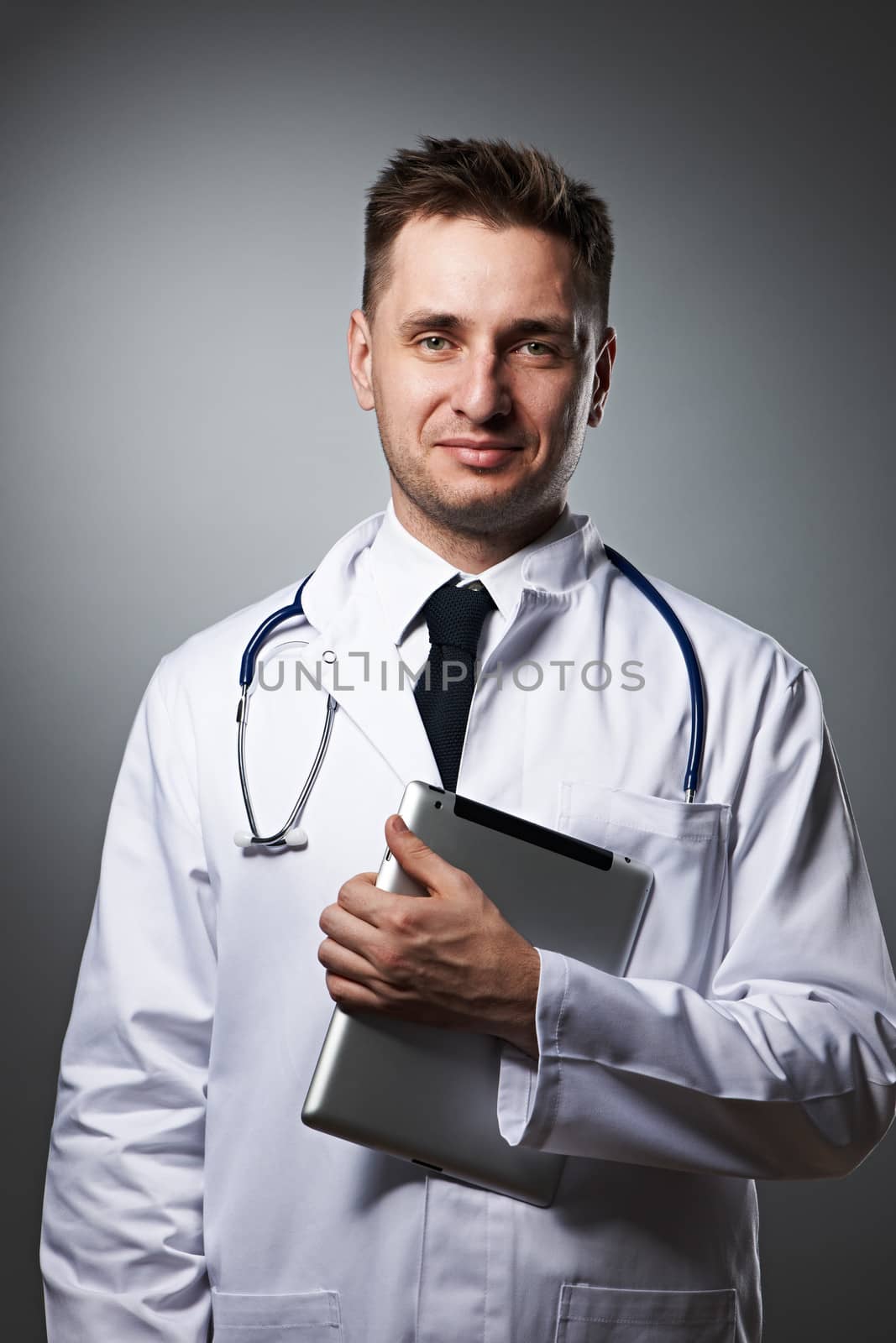 Medical doctor with tablet pc portrait against grey background 