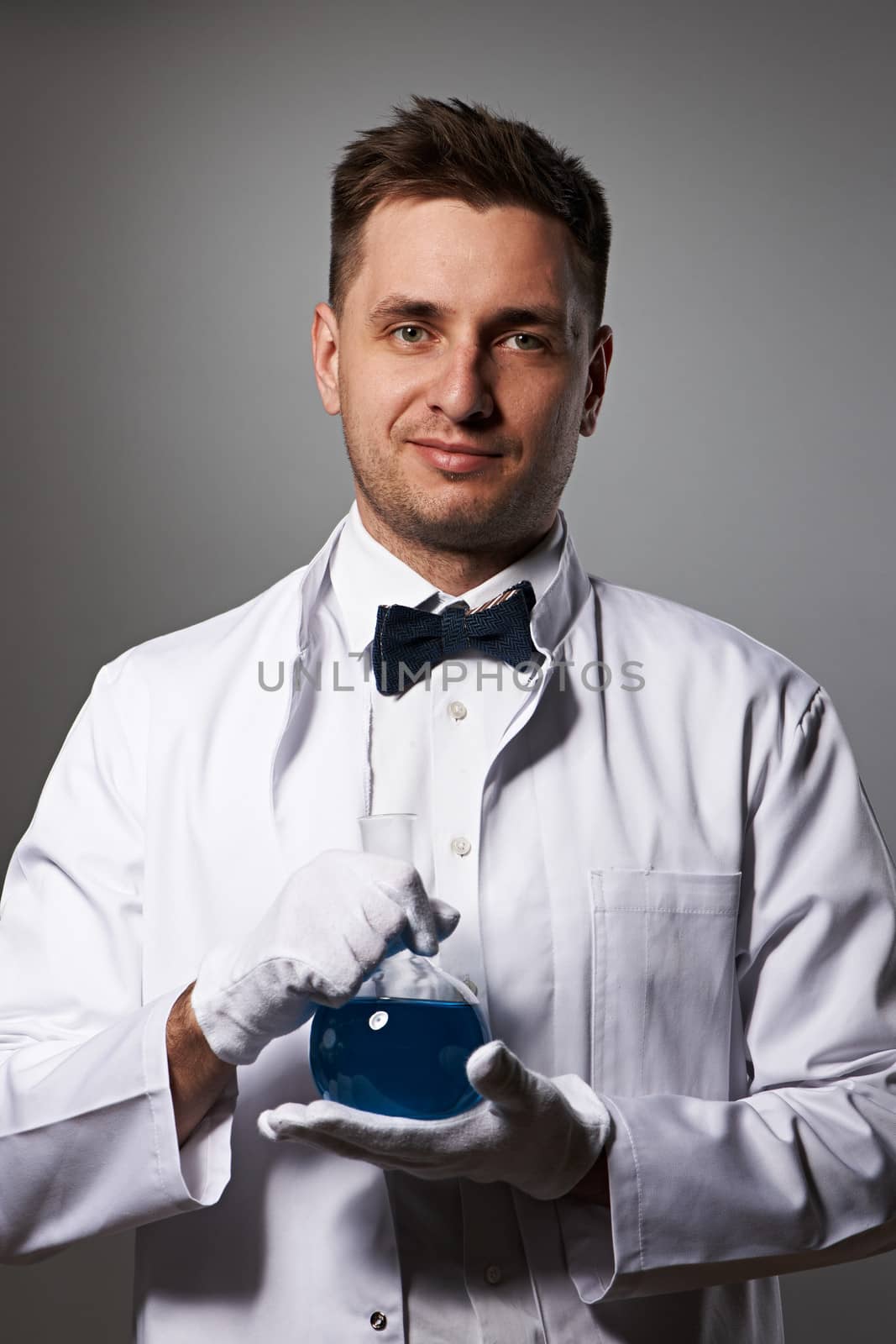 Scientist with chemical flask against grey background