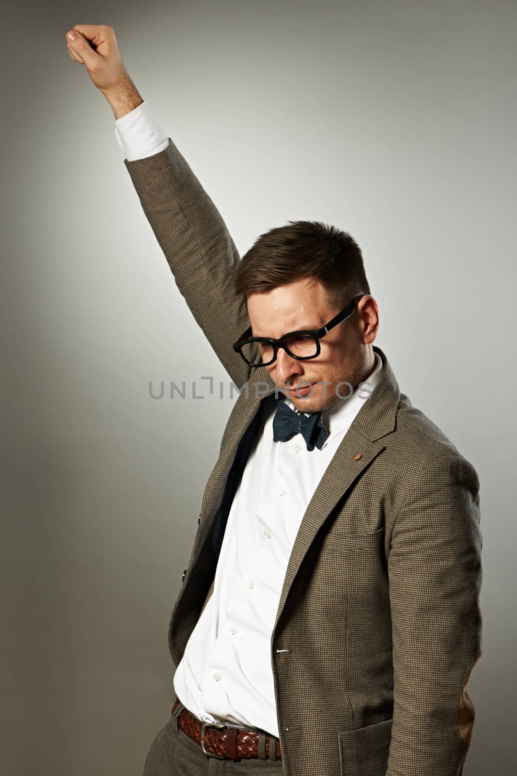 Superhero nerd in eyeglasses and bow tie against grey background