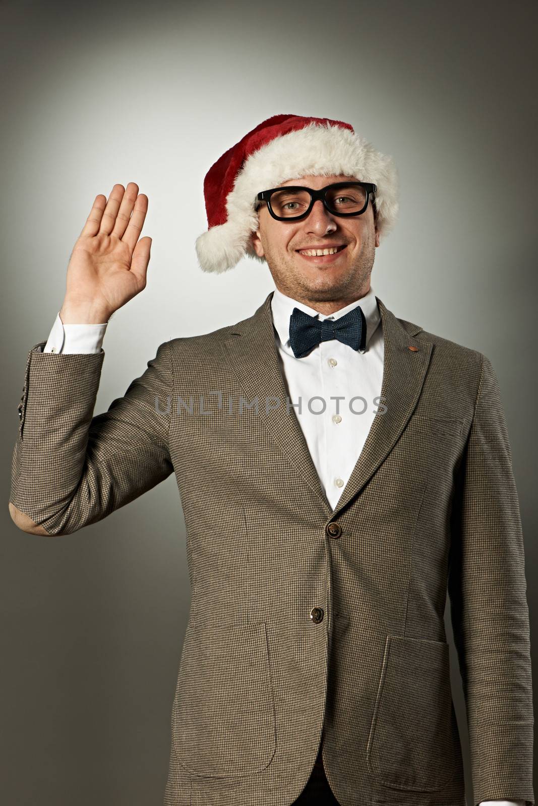 Confident nerd in Santa Claus hat and bow tie celebrates Christmas