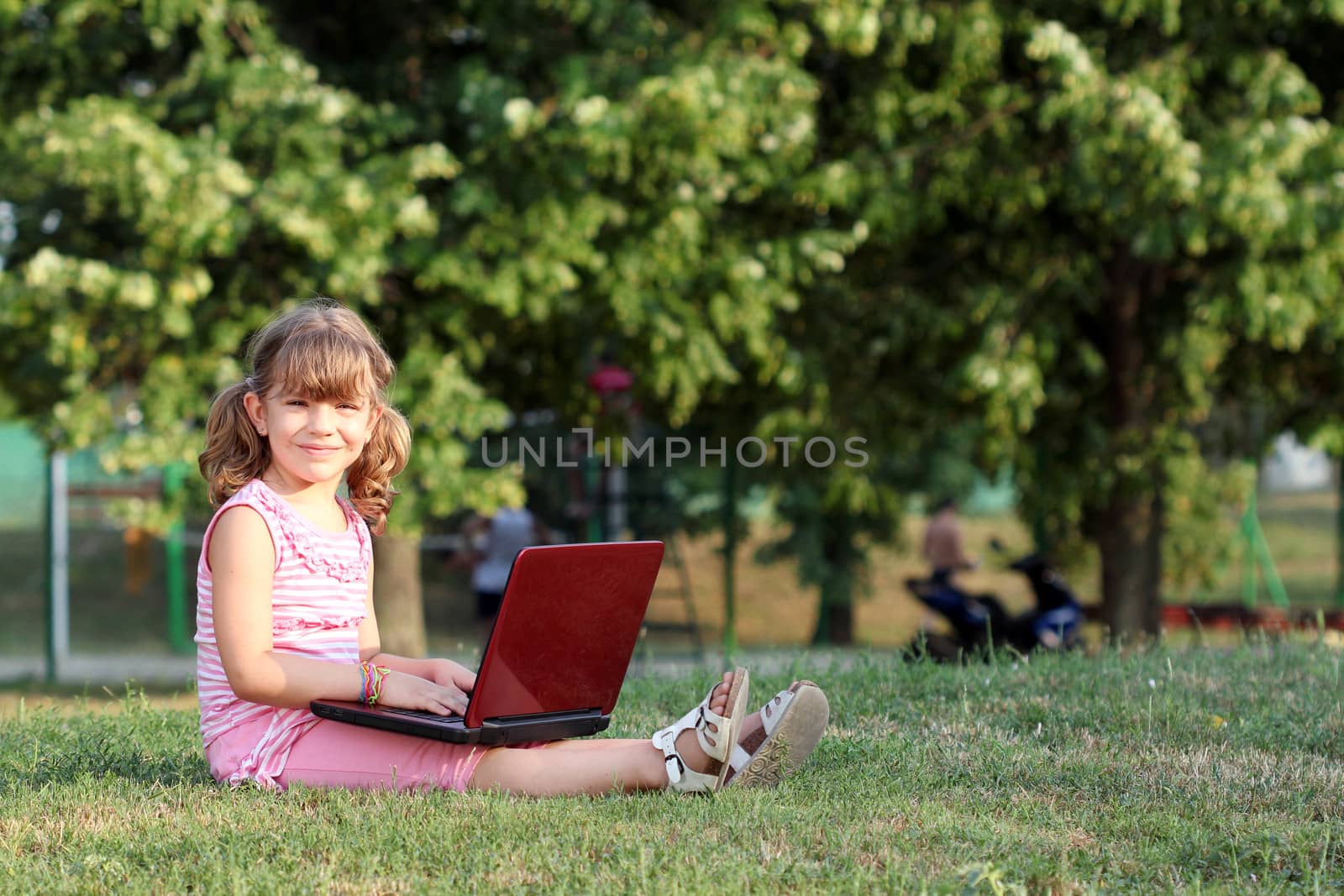 beautiful little girl with laptop in park