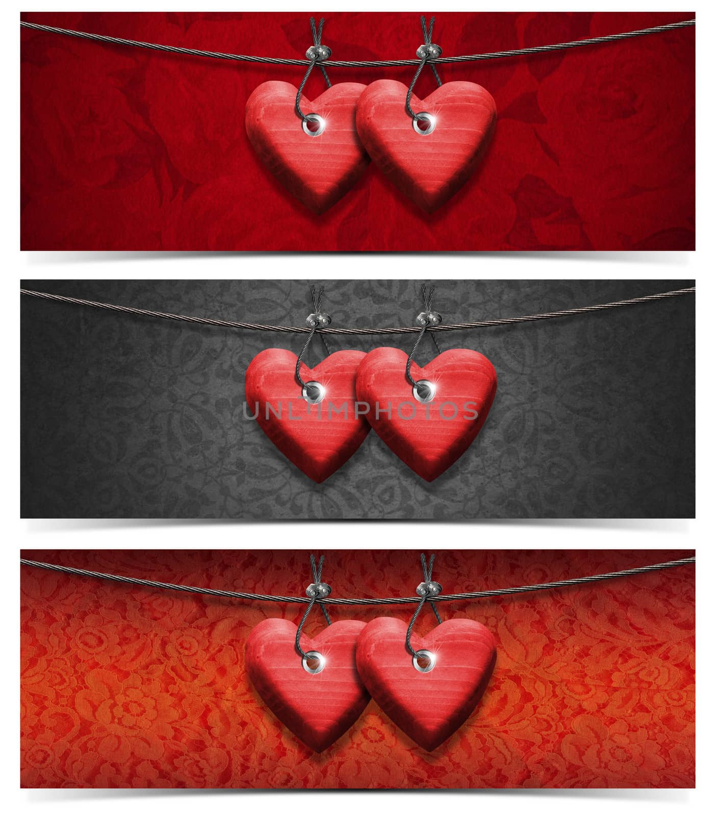 Two handmade red wooden hearts hanging on a steel cable on fabric background
