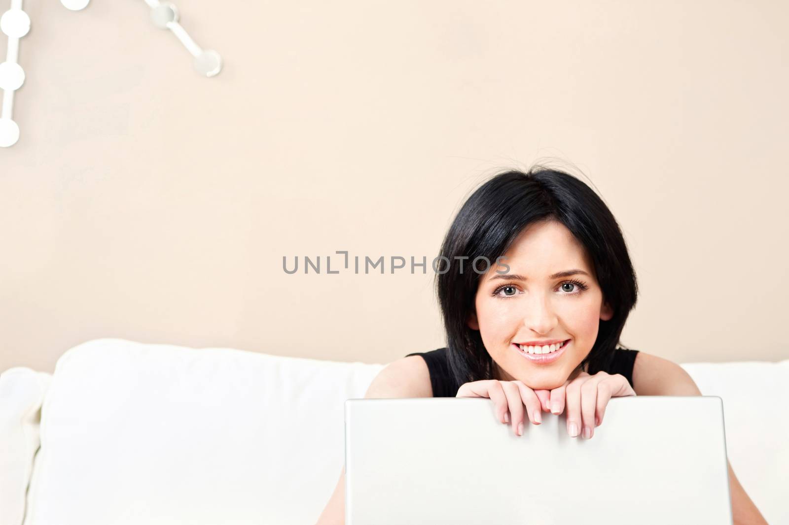 Pretty girl on white sofa with laptop at home