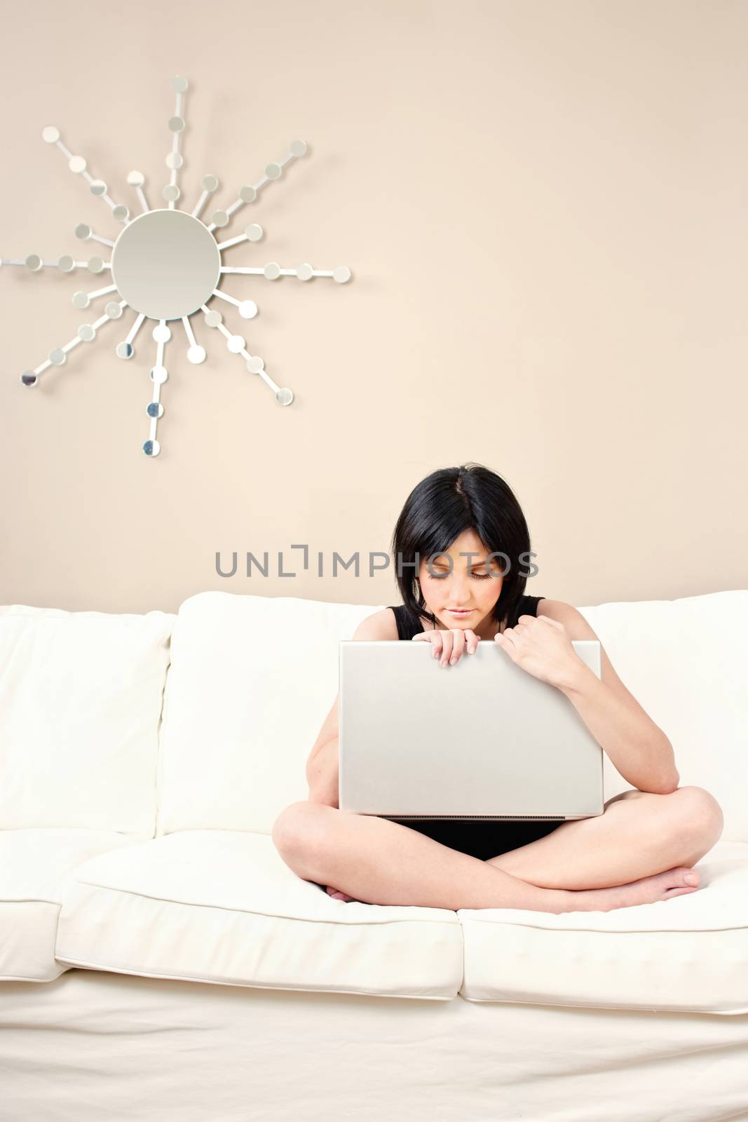 Pretty girl on white sofa with laptop at home