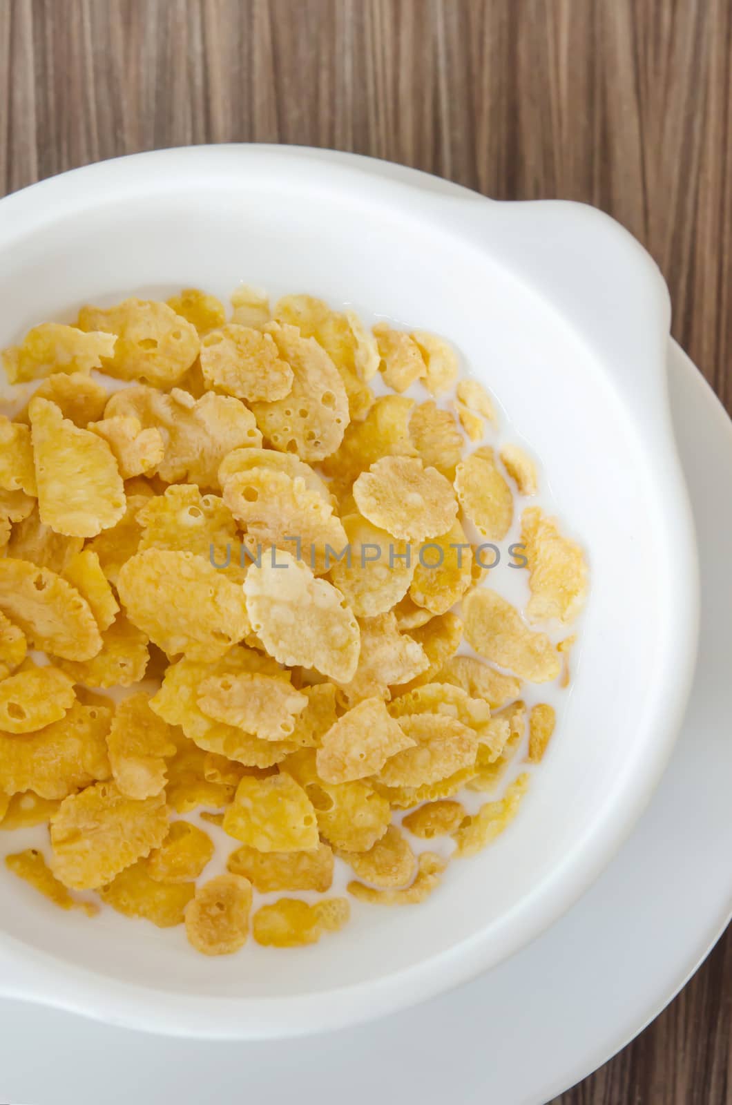 top view corn flake  with fresh  milk in white bowl 