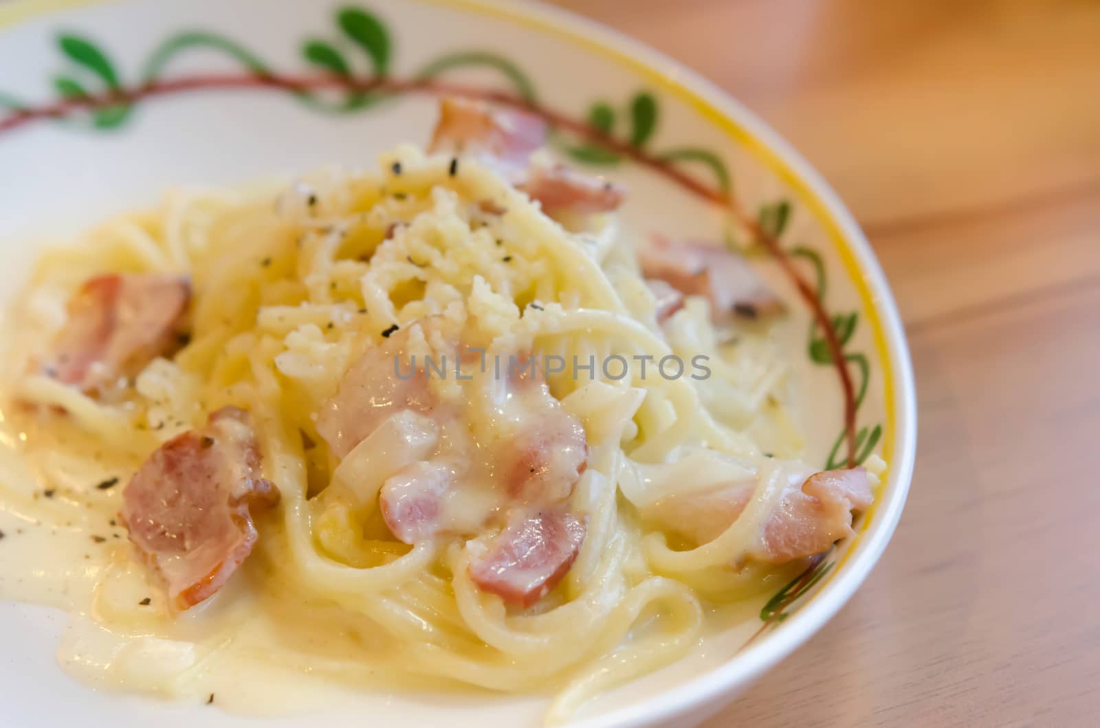 close up spaghetti carbonara with bacon and cheese on dish over wooden table