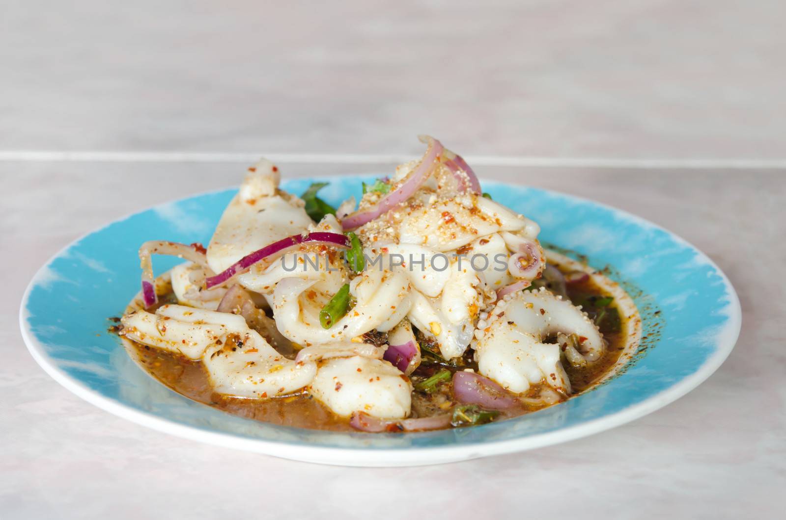 spicy seafood salad with squid and chili sauce on blue dish