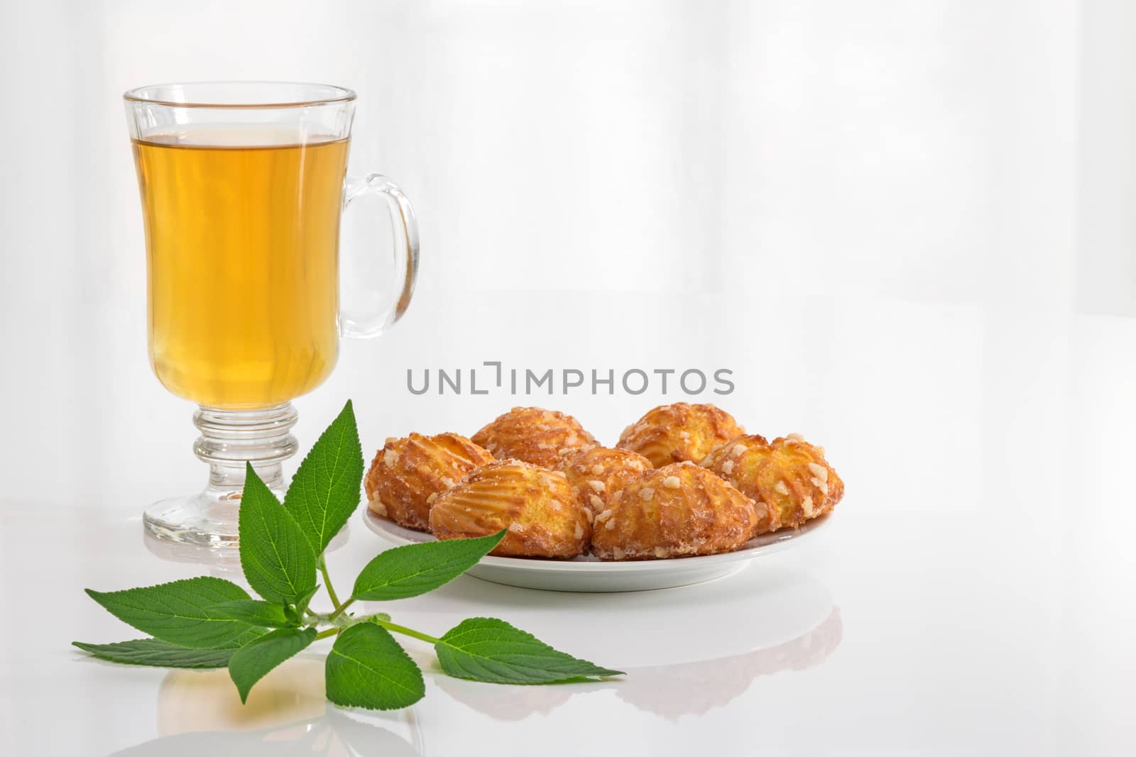 Tea in a glass cup, fresh mint leaves and tasty cookies.