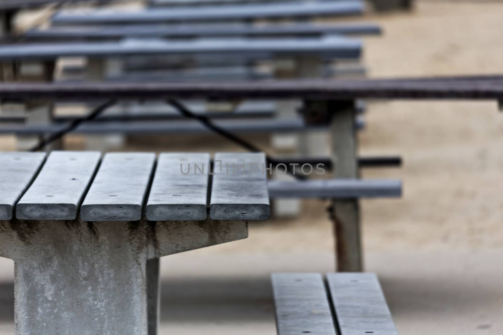 Empty picnic tables, lined up, with selective focus on weathered front table; location is New Jersey shore, Brigantine and Ventana area; 