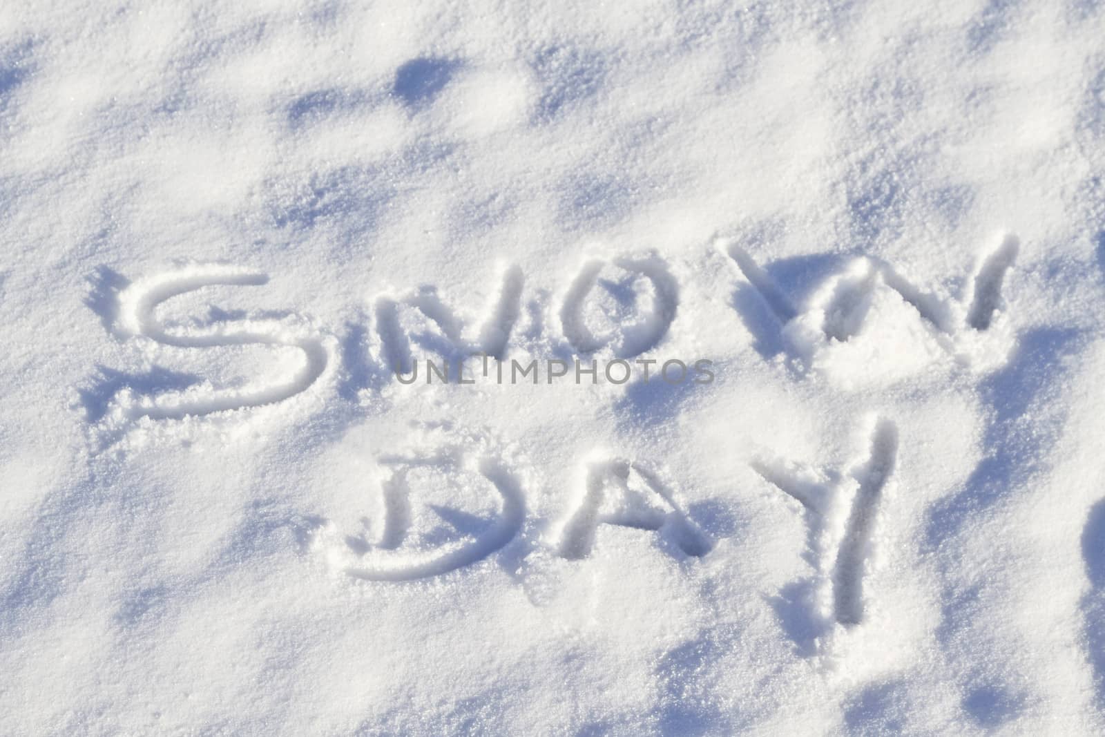 Snow Day written in capital letters in fresh snowfall signifies No School