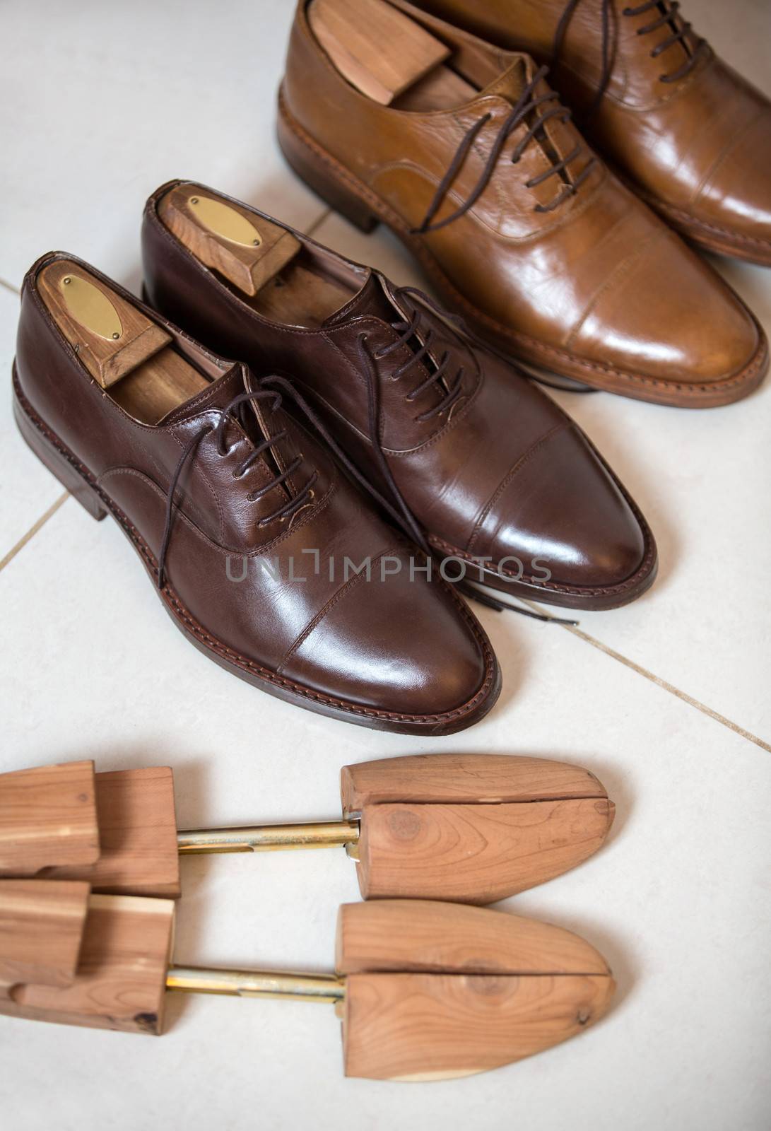 Two pairs of brown handmade classic men's shoes  with a shoe pads and stretchers inside and beside the shoes