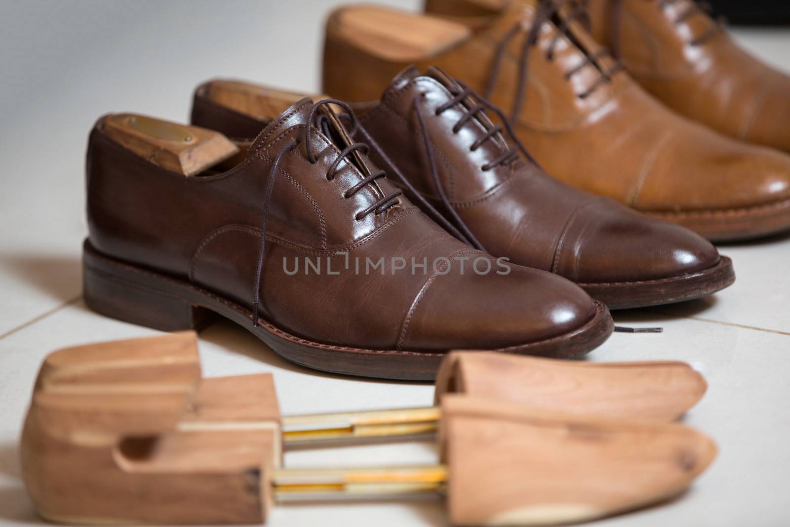 Two pairs of brown handmade classic men's shoes  with a shoe pads and stretchers inside and beside the shoes