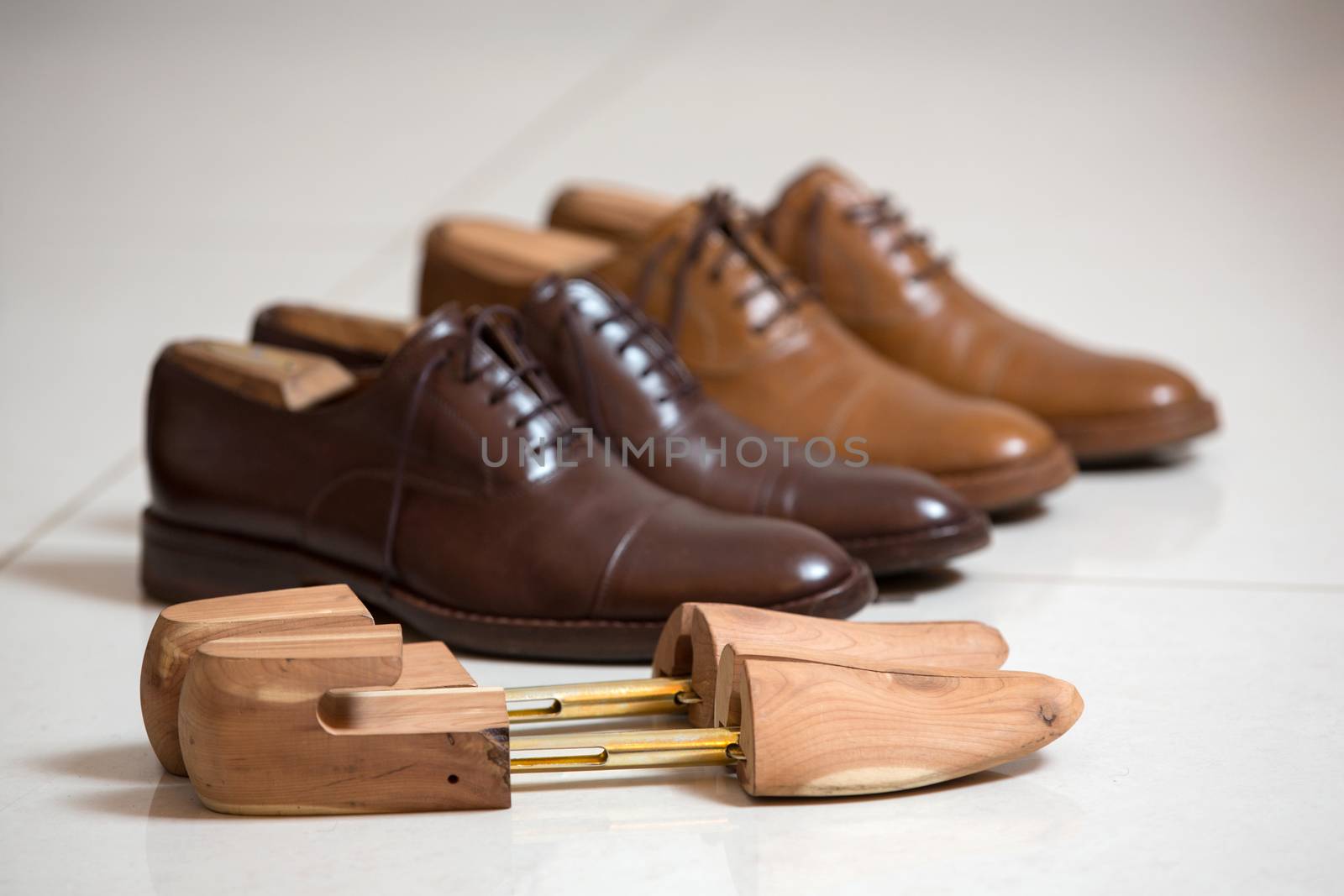 Two pairs of brown handmade classic men's shoes  with a shoe pads and stretchers inside and beside the shoes