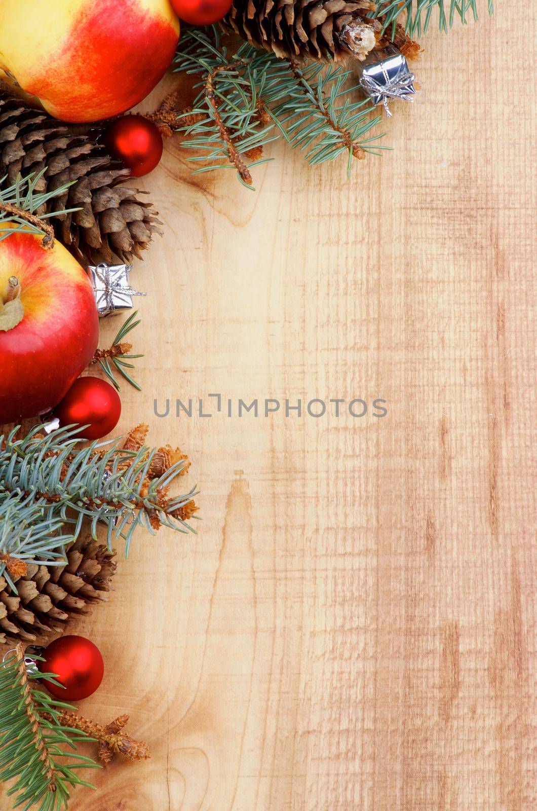 Corner Border of Spruce Branch, Red Baubles, Fir Cones and Delicious Apples closeup on Wooden background. Vertical View