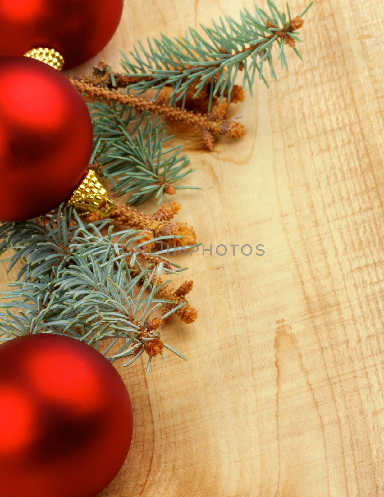 Corner Border of Green Spruce Branch with Fir Cones and Red Baubles closeup on Wooden background