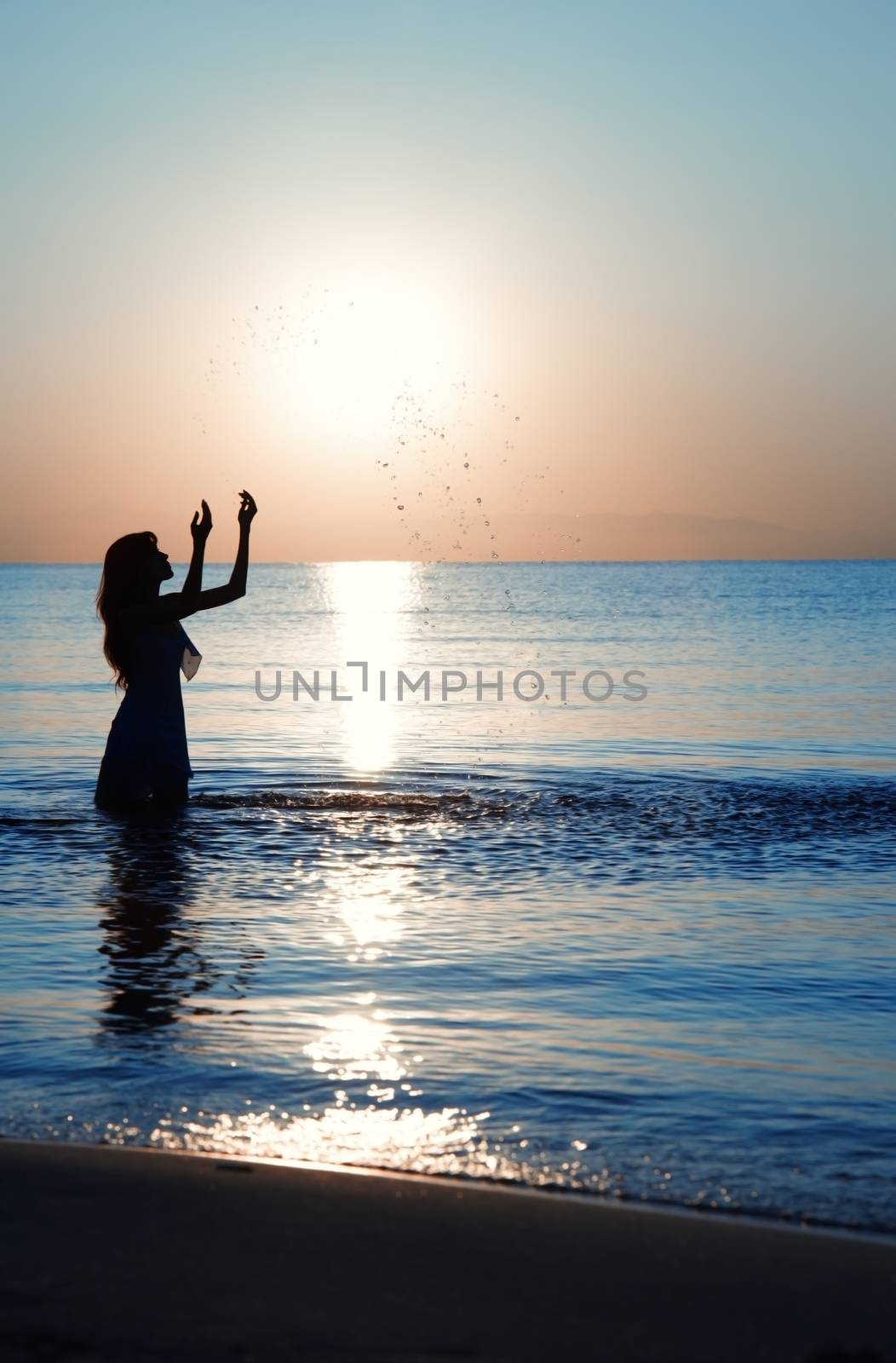 Silhouette of the lady playing with water during sunset