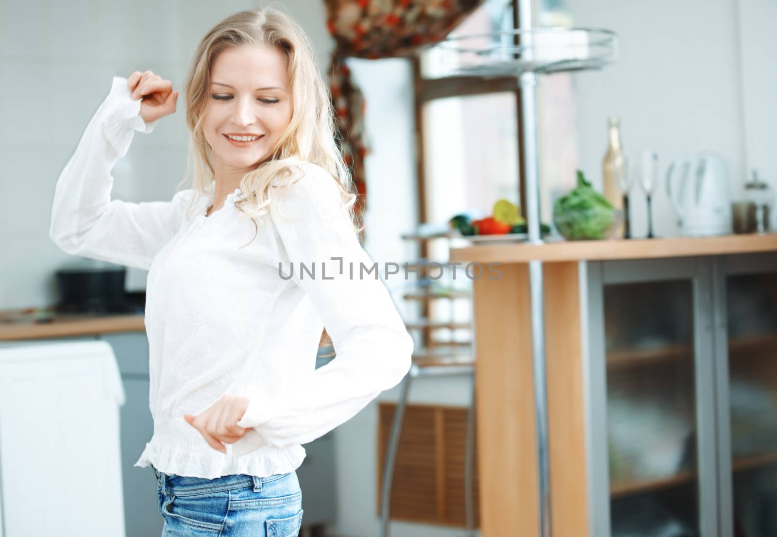Smiling blond lady dancing at the kitchen
