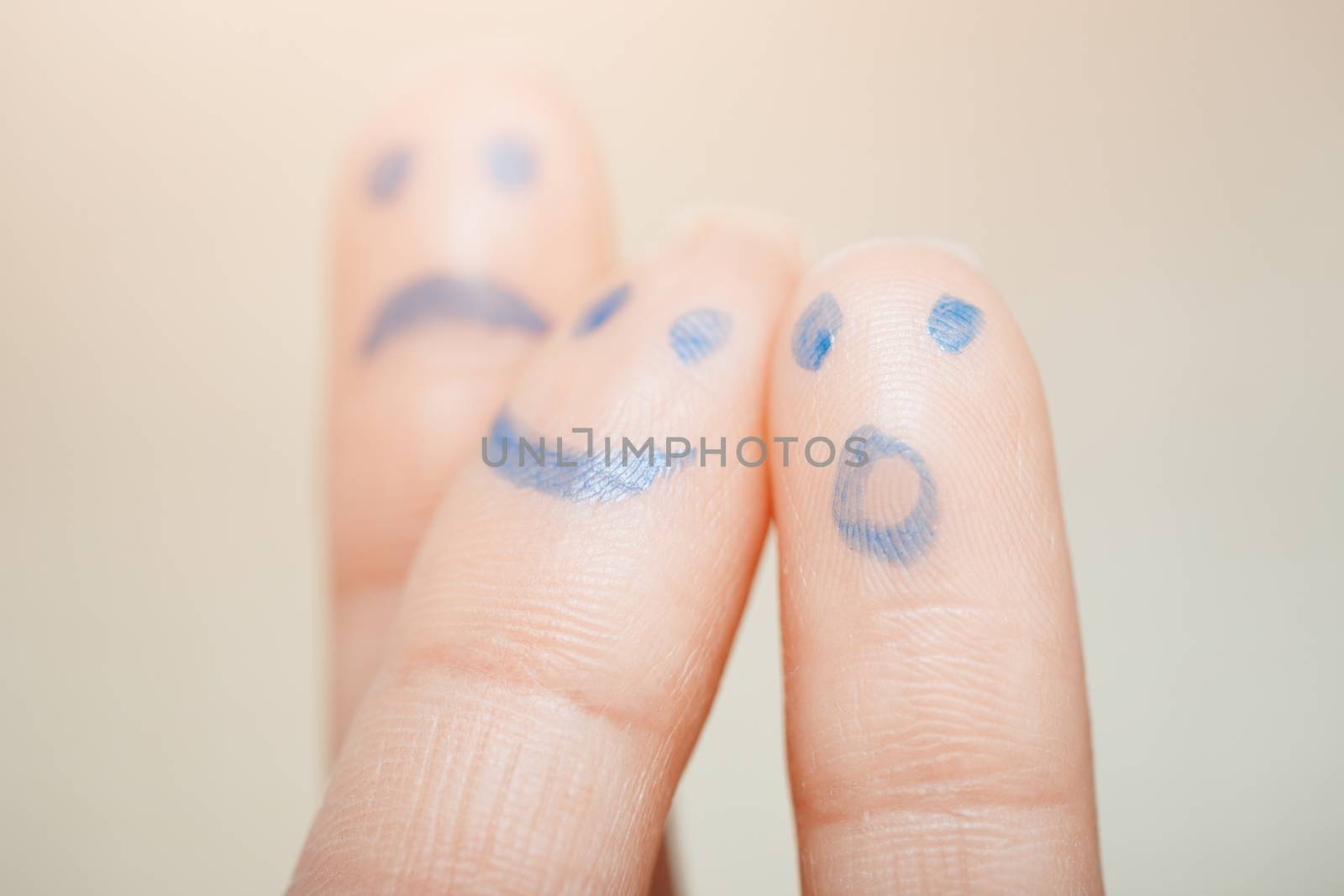 Three fingers with painting of various emotional faces