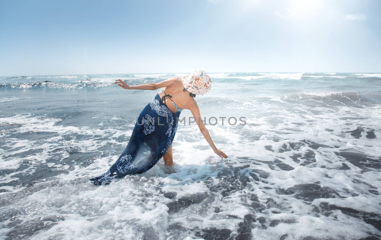 Woman playing with waves at vacation. Rear view