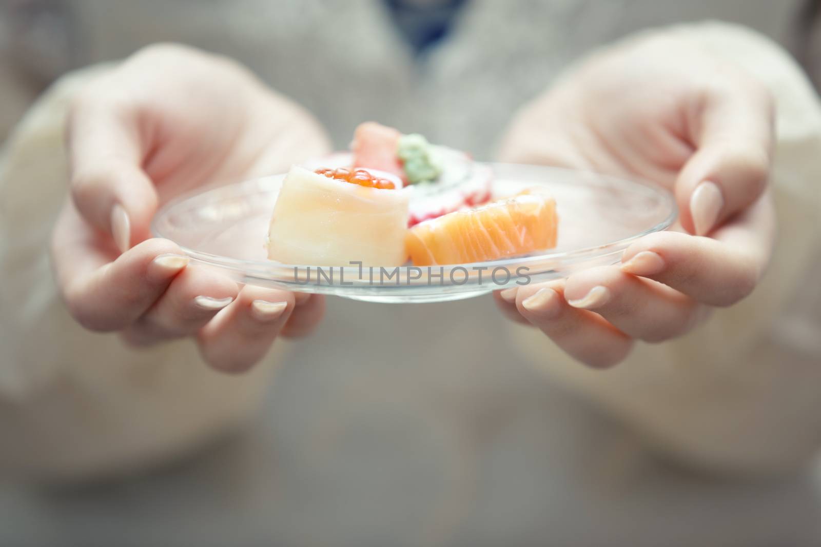 Human hands holding plate with sushi