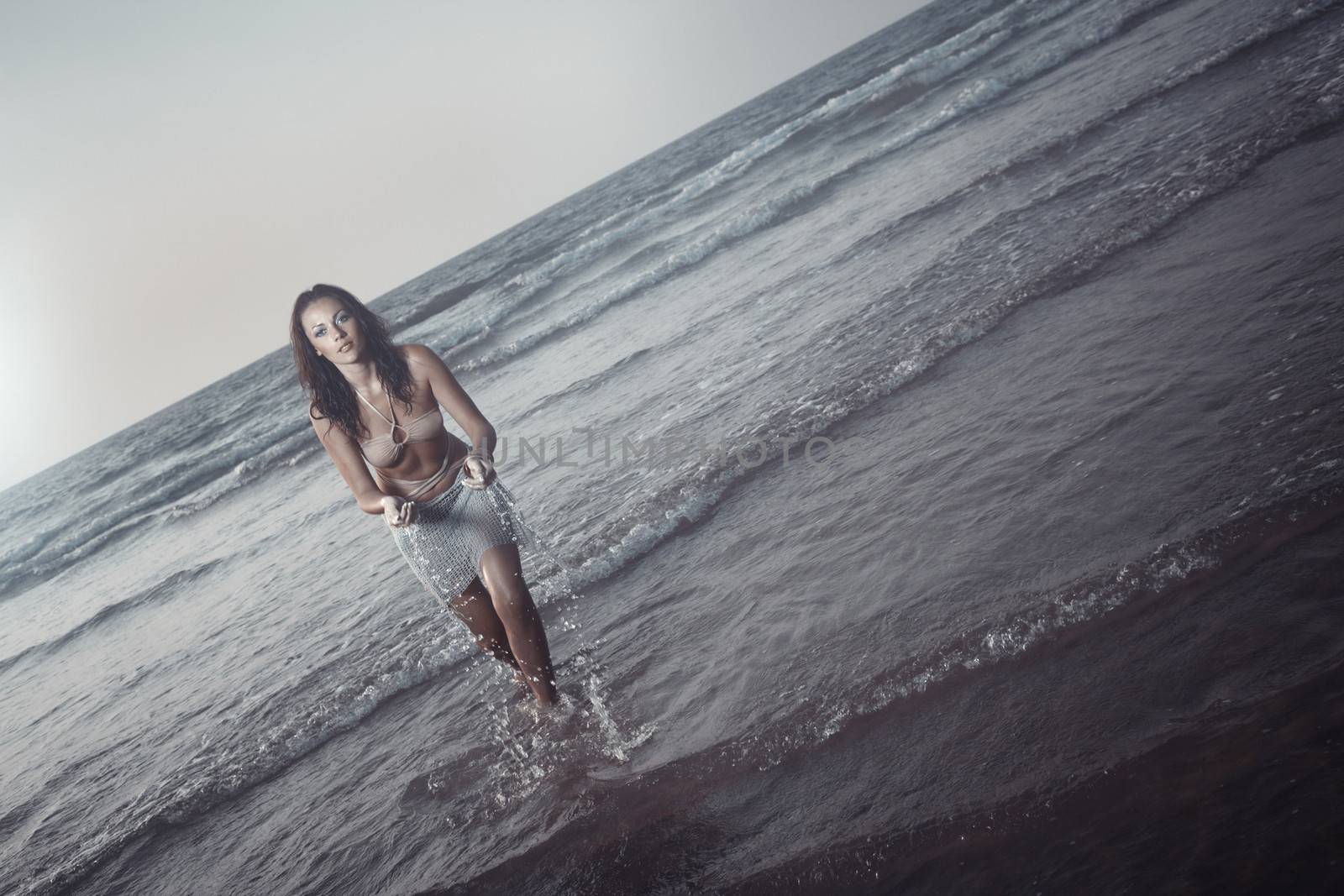 Young adult woman splashing at the evening beach