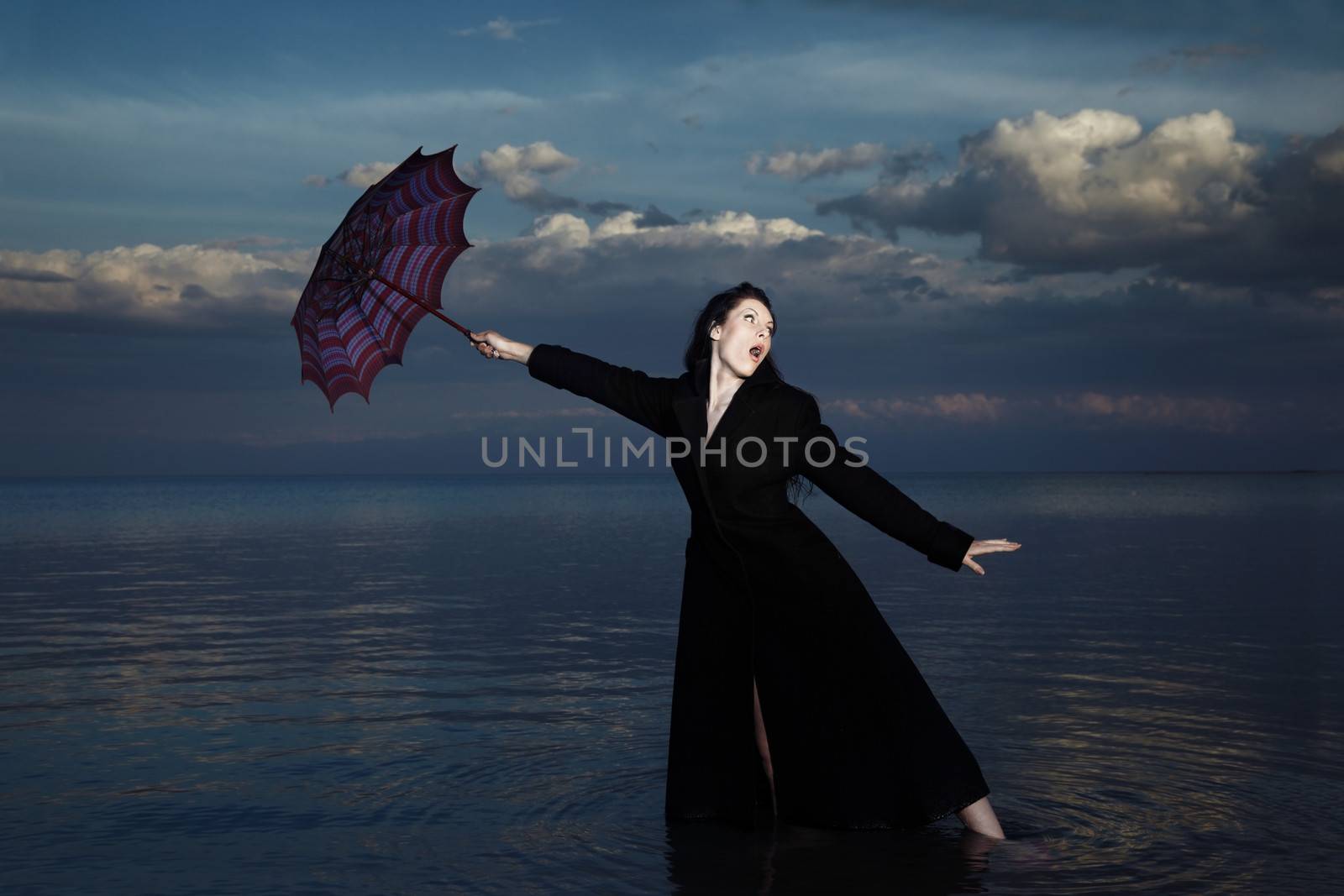 Businesswoman in the water with blown umbrella