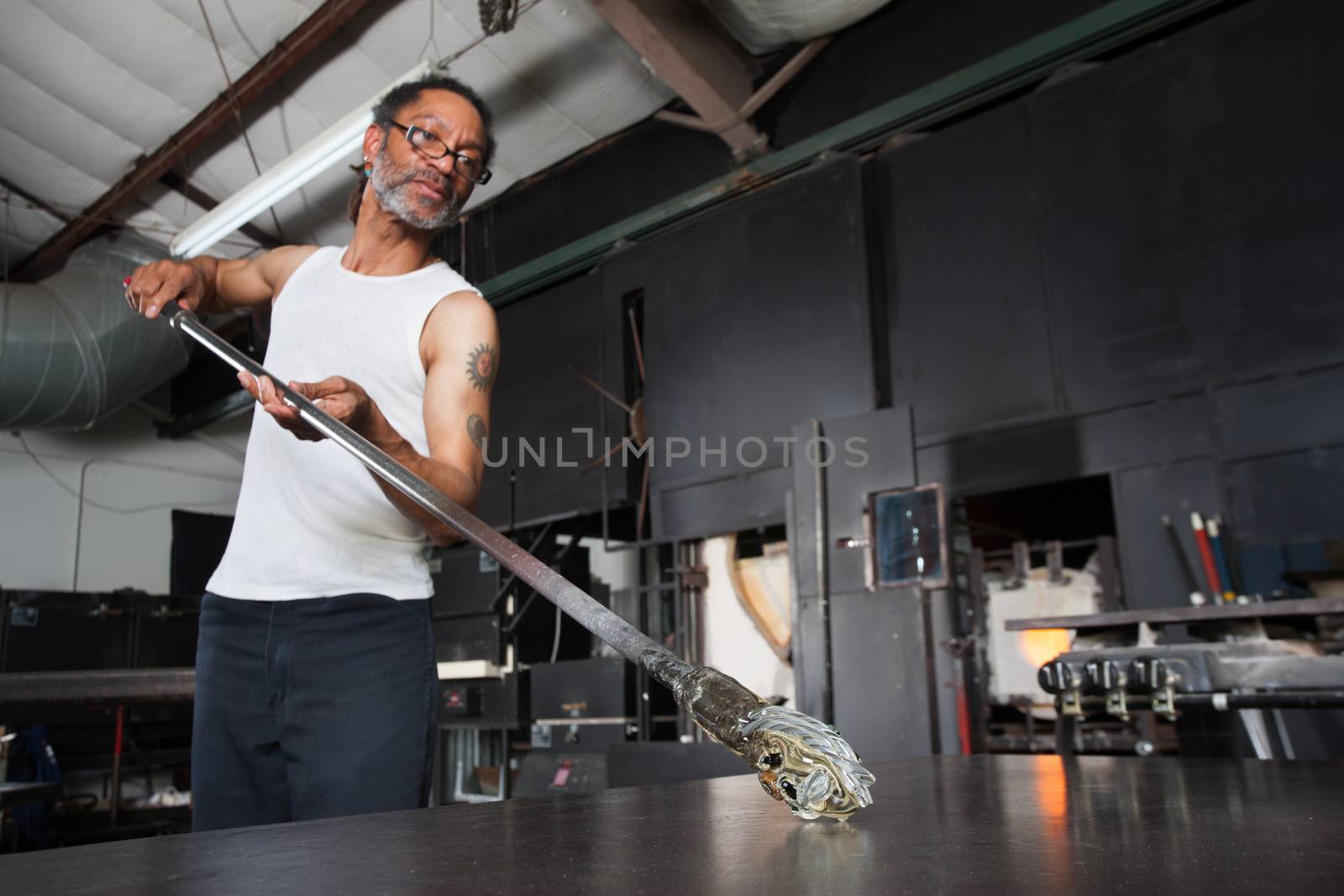 Mature glass artisan turning rod with small vase